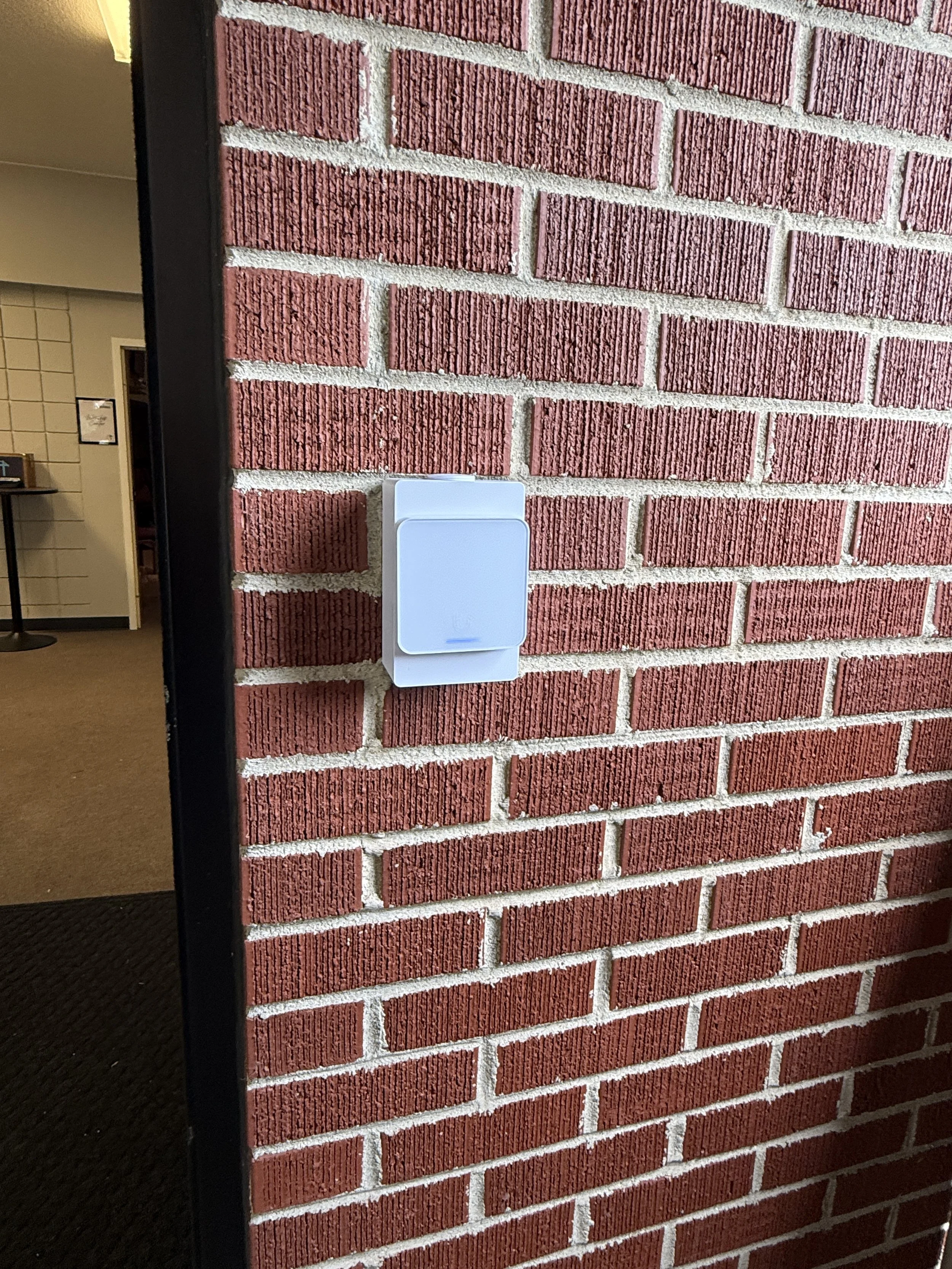 Wall-mounted access reader beside a commercial entry door on a brick wall, Dayton OH access control installation