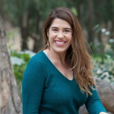 Courtney McCall, adQuadrant, smiling outdoors in a park with trees and greenery.