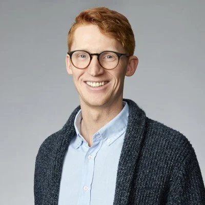 Jonathan Goodkey – BDC BDC Capital, wearing a light blue shirt and a dark gray cardigan, against a gray background.