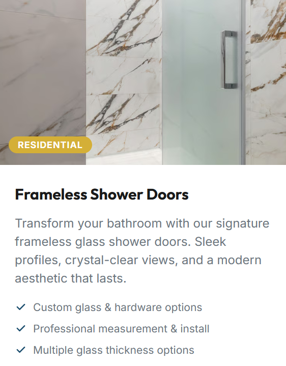 Interior of a bathroom shower with frosted glass frameless shower door, marble wall tiles with gold and black veining, and a chrome handle.