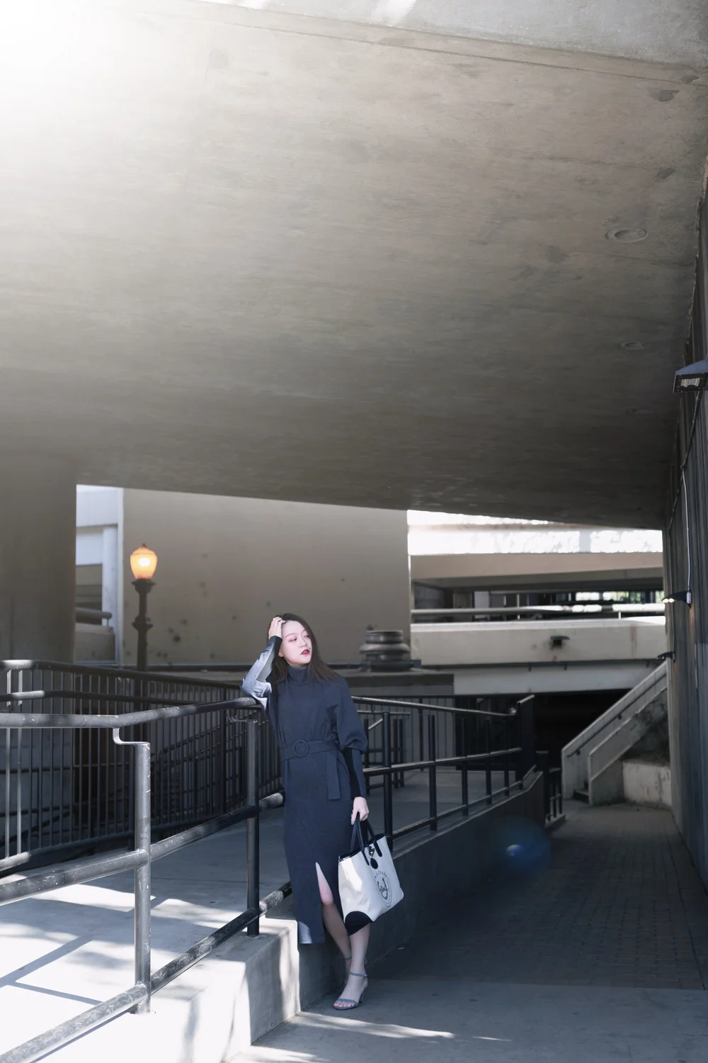 A woman in black framed by concrete architecture and natural light