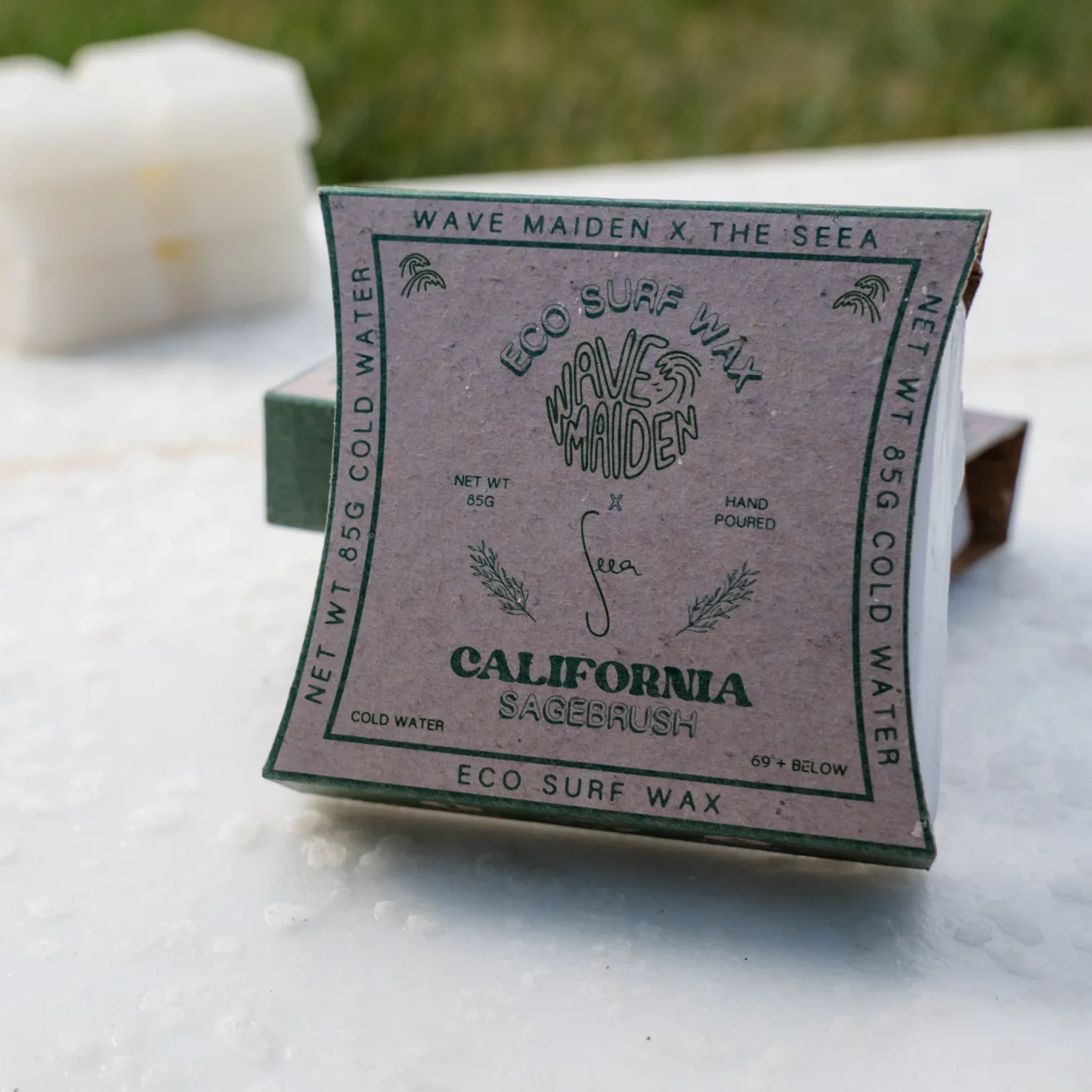 A box of California Sagebrush eco surf wax with a light purple background and green text, featuring illustrations of sage leaves and waves.
