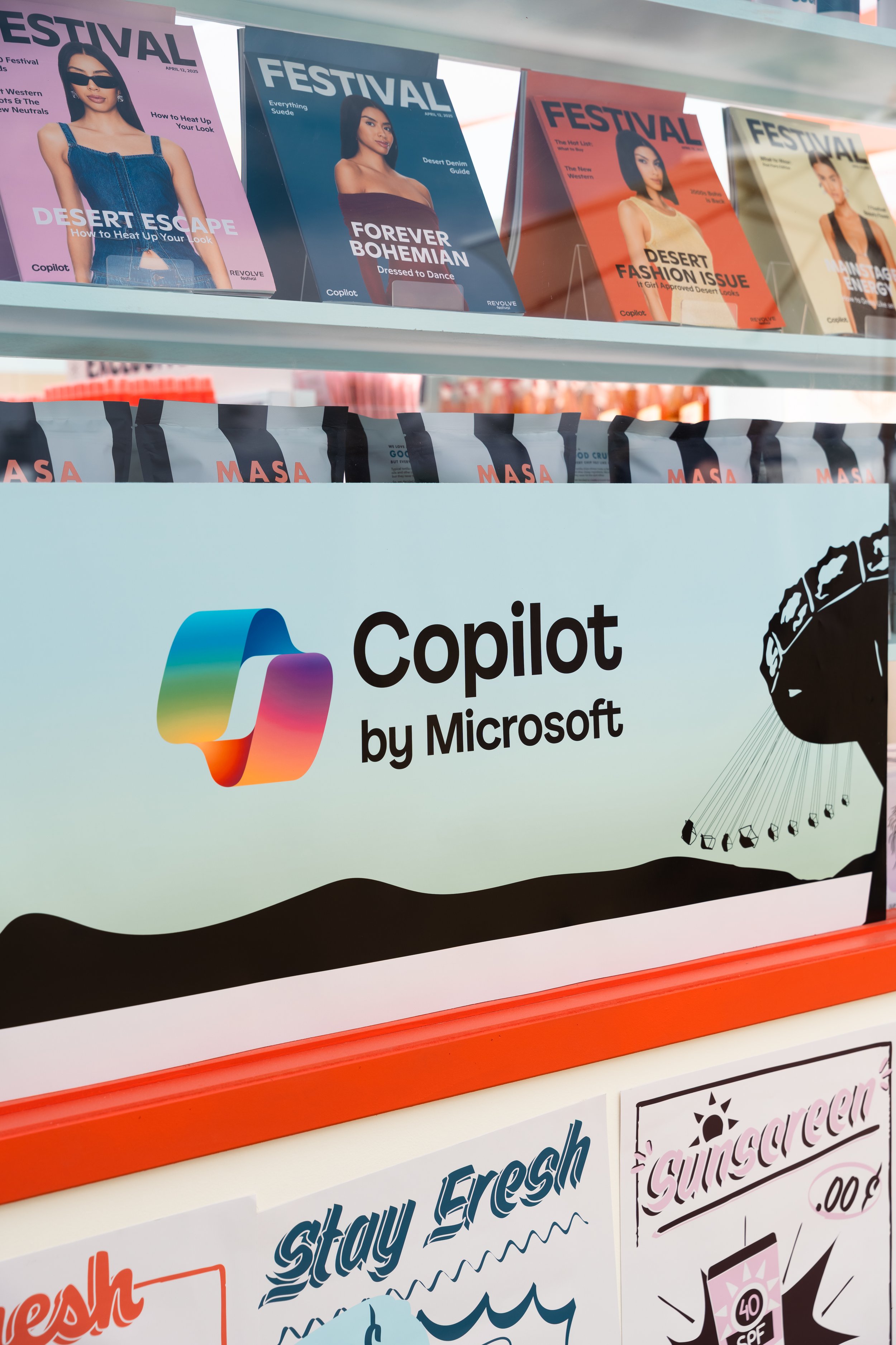 Display with 'Festival' magazines, 'Masa' chips, and 'Copilot by Microsoft' signage at an event or store setting.