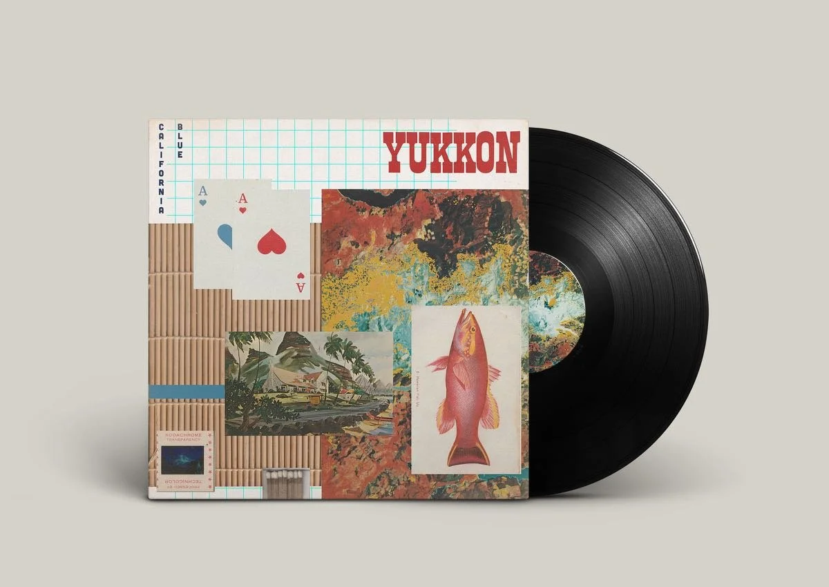 A vinyl record and illustrated album cover titled "Yukon" with a collage of colorful abstract artwork, a pair of playing cards, a painting of a landscape, and an illustrated fish.