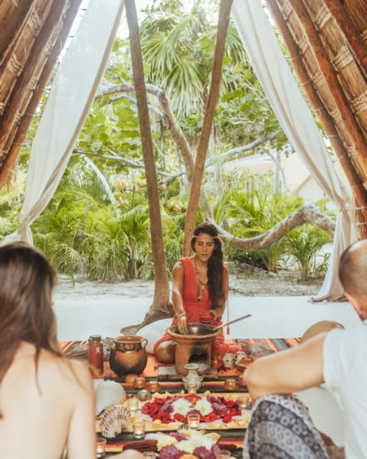 Private couples cacao ceremony at Medicine Wheel Tulum. A practitioner in traditional dress leads a heart opening ritual inside our sacred bamboo shala.