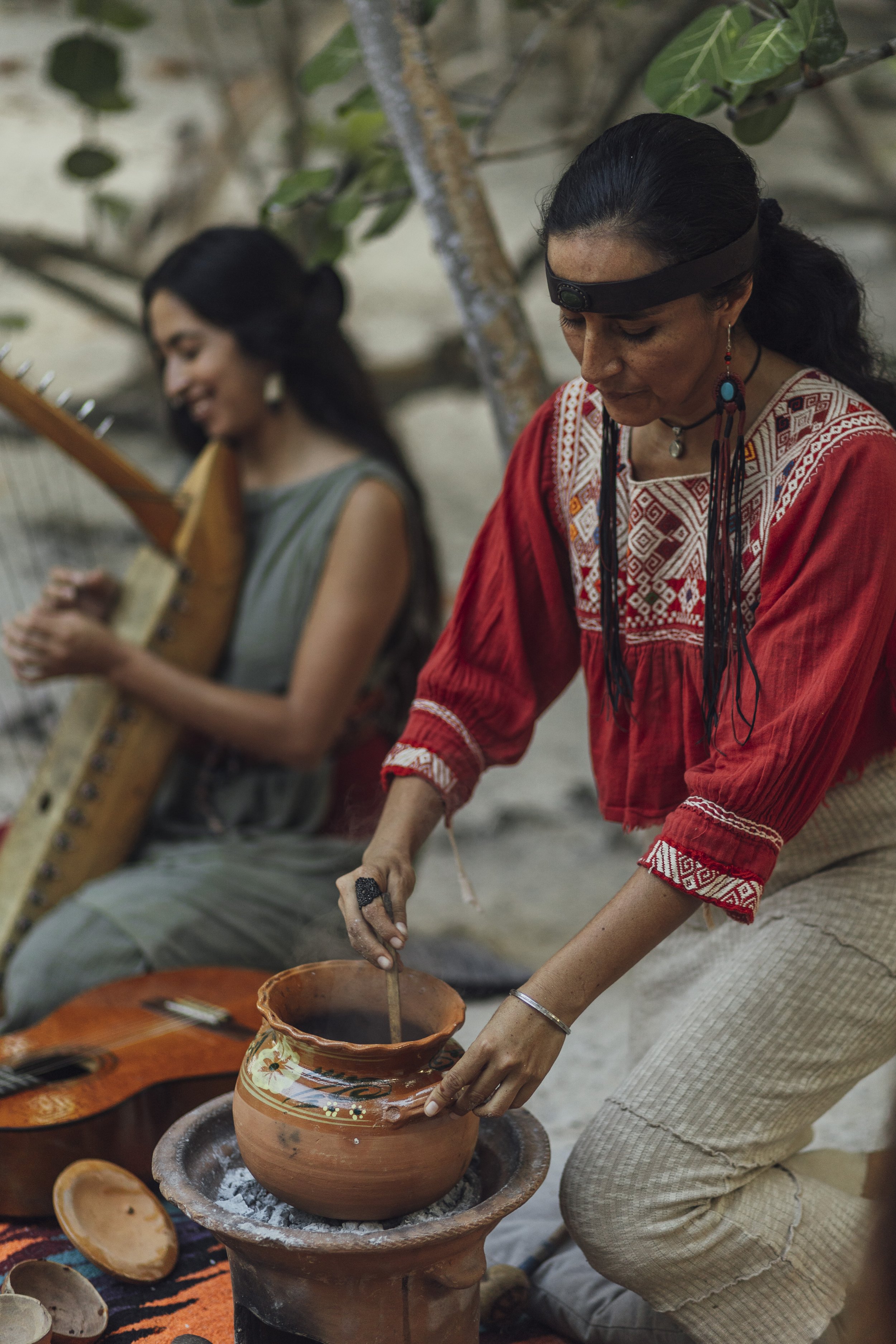 Private cacao ceremony at Medicine Wheel Tulum. Practitioners in traditional dress prepare ceremonial cacao and play sacred harp music in a jungle sanctuary.
