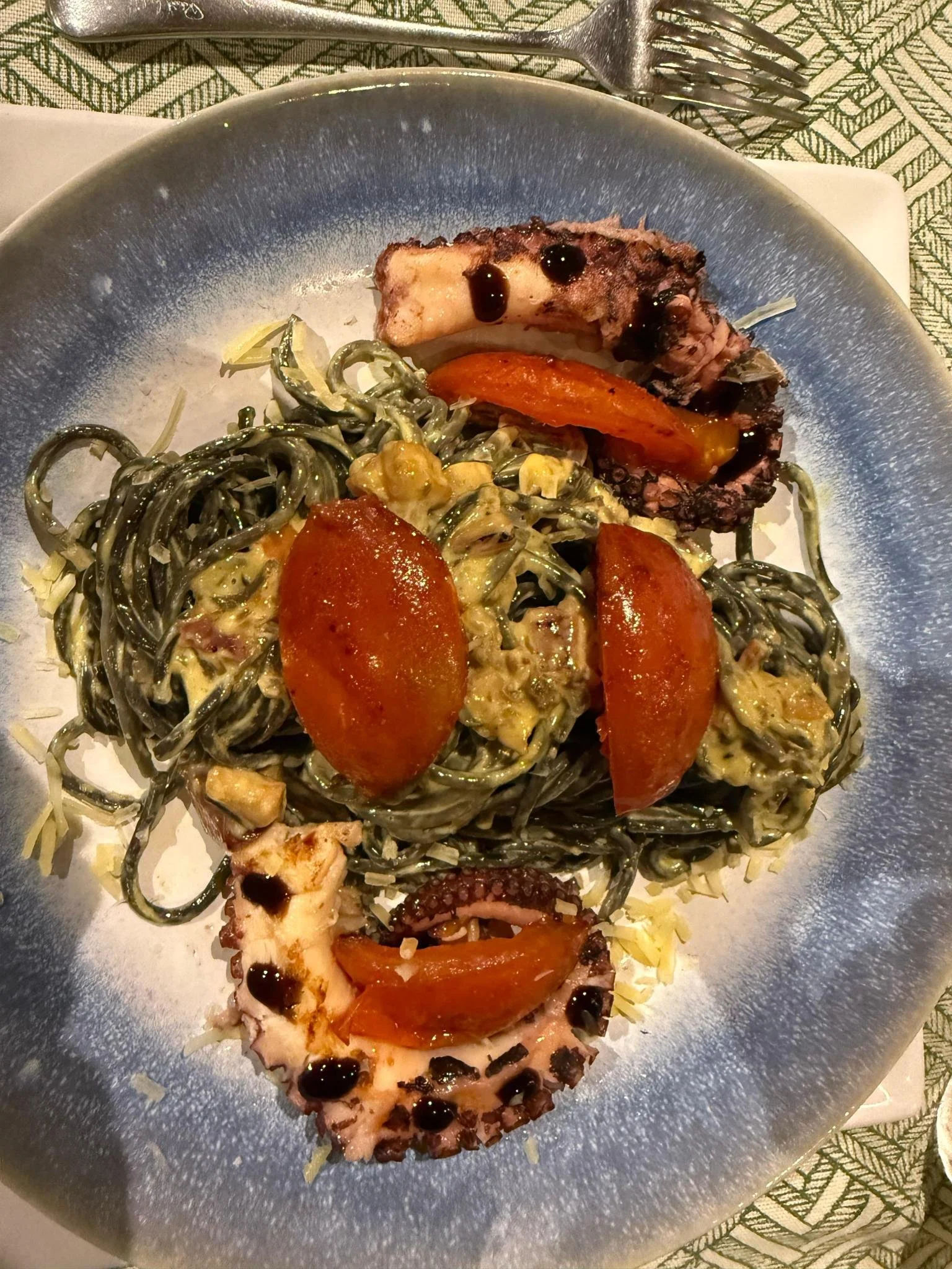 Grilled octopus with black squid ink pasta and roasted tomatoes served in the Amazon rainforest, Ecuador