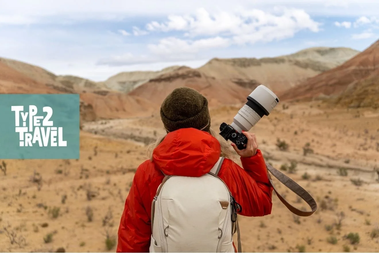 Photographer holding camera in arid mountainous area.
