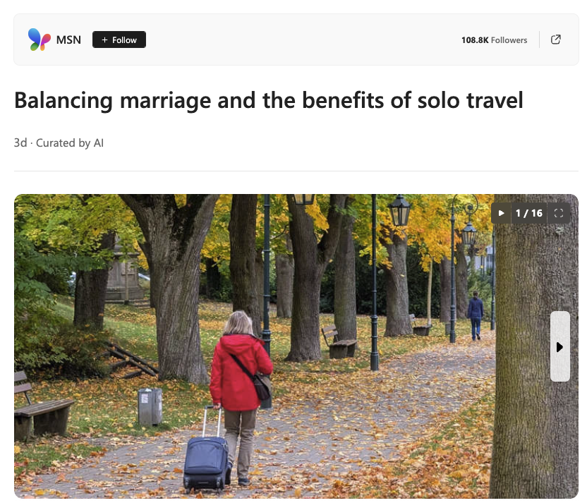 Woman in red jacket pulling rolling suitcase walking along park path lined with trees and benches in autumn.