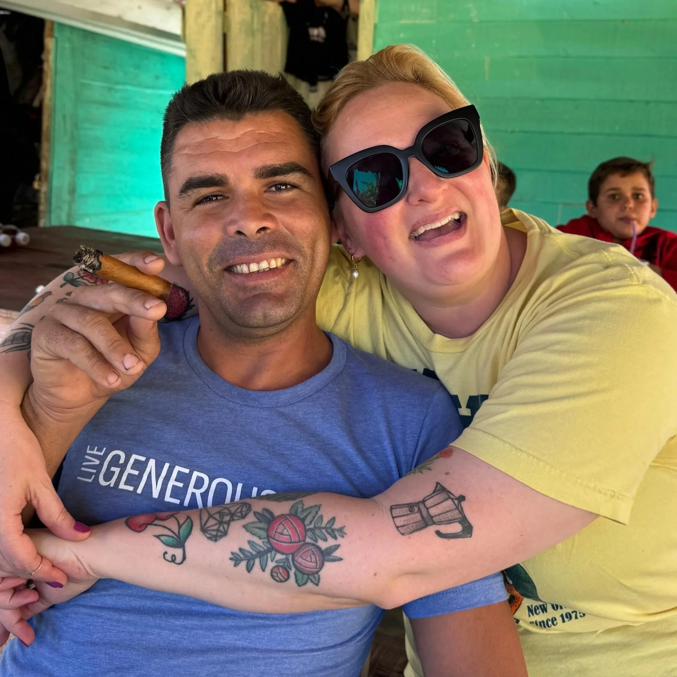 Travel guide and tourist sharing cigars and smiling together in rustic Cuban home with thatched roof