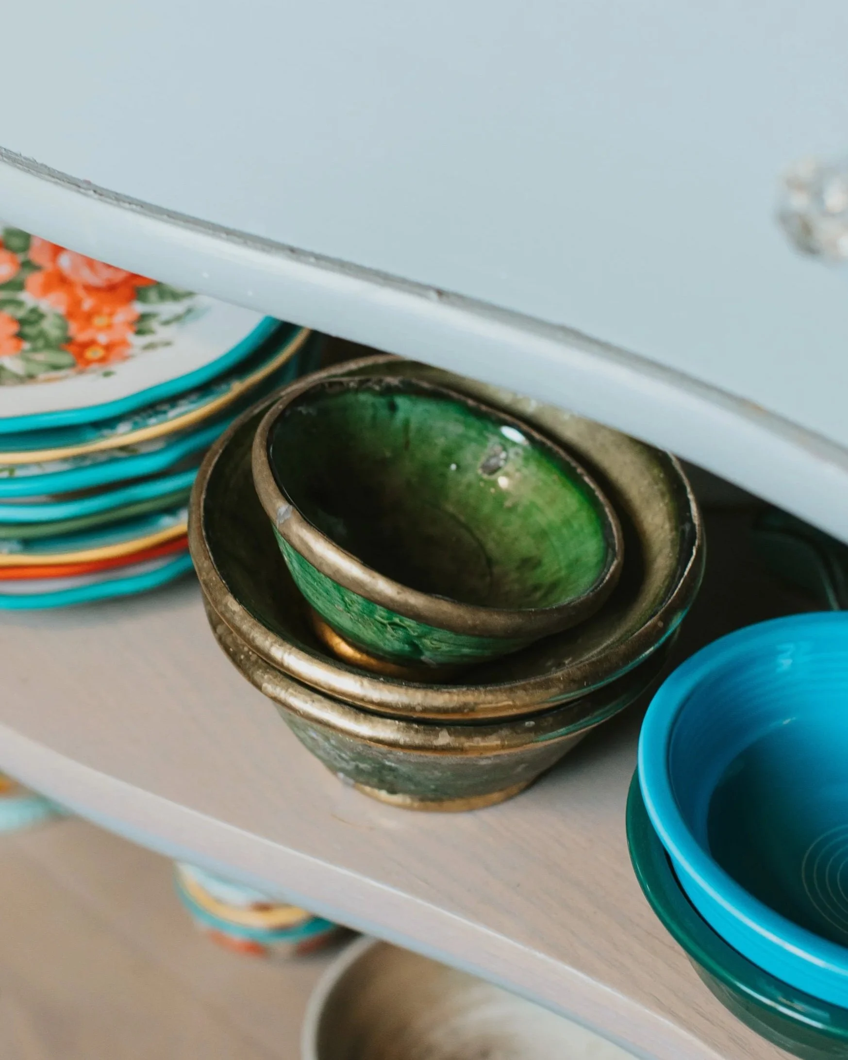 Collection of green Tamegroute pottery bowls and a Moroccan tagine on a shelf.