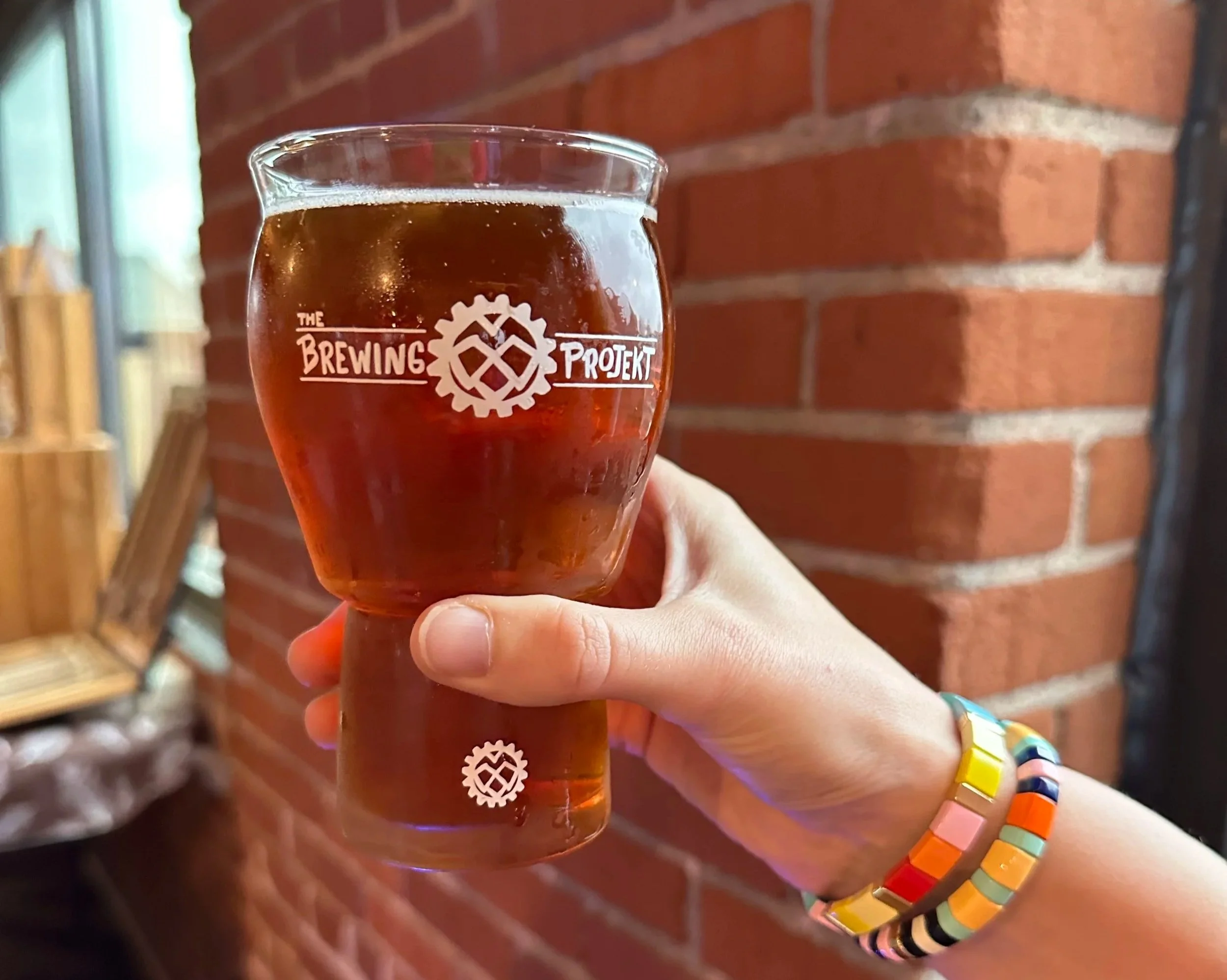 A person holding a cold beer on the patio of an Eau Claire brewery on a sunny summer afternoon.