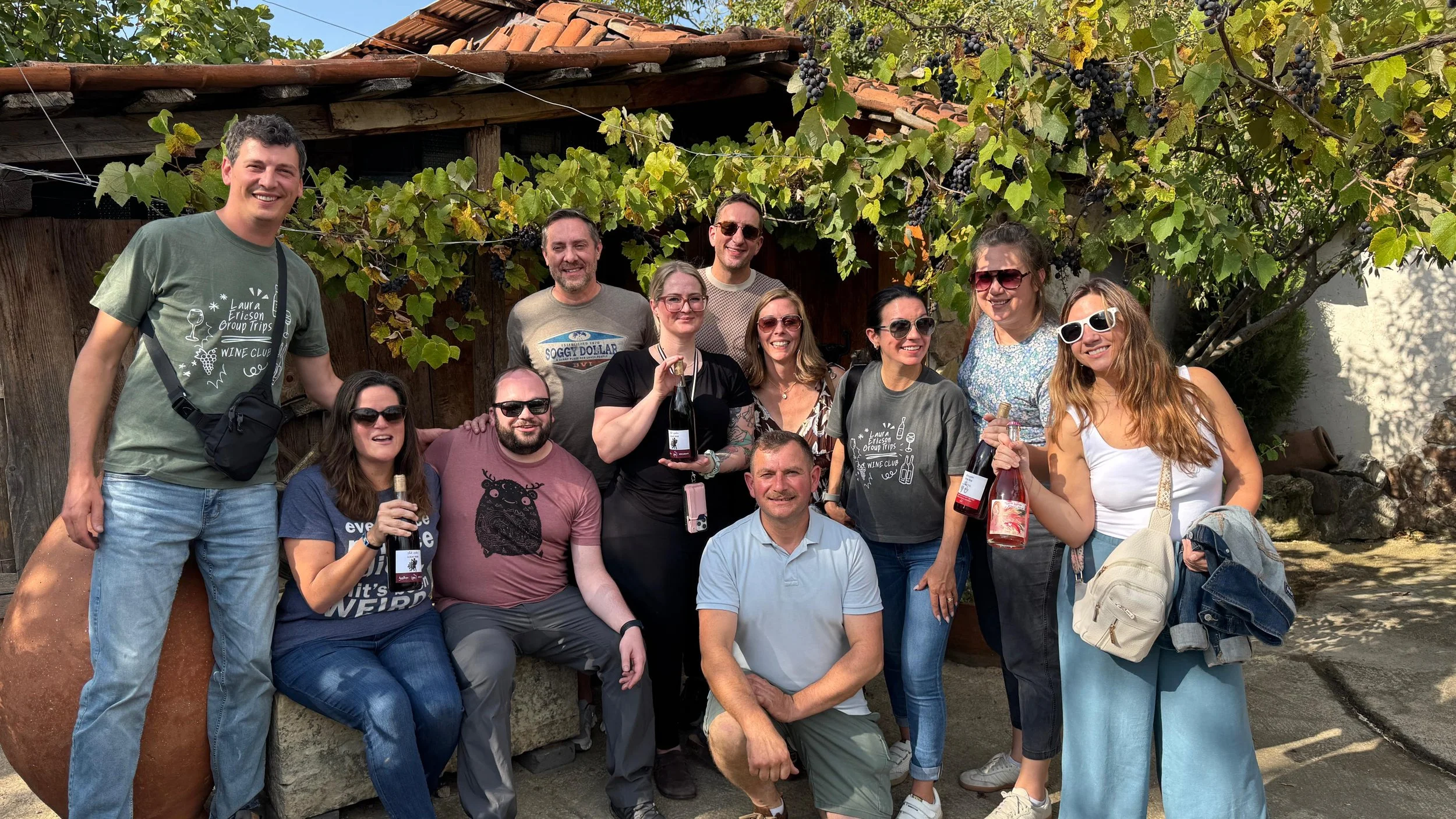 Travel group posing with wine bottles at local Georgian winery, group travel experience in Georgia