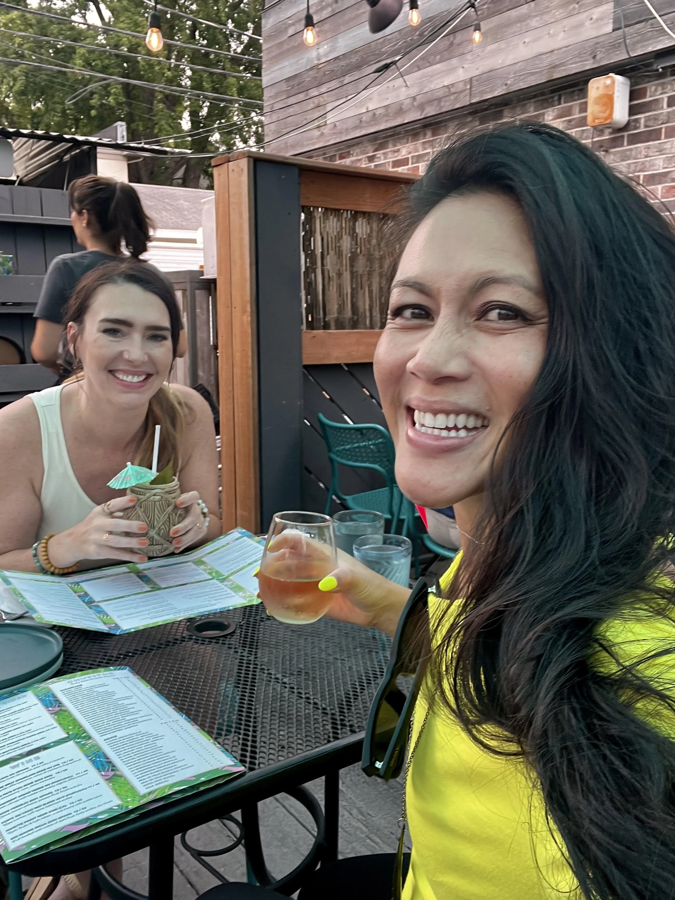 Two women sitting at an outdoor table at a restaurant or bar.