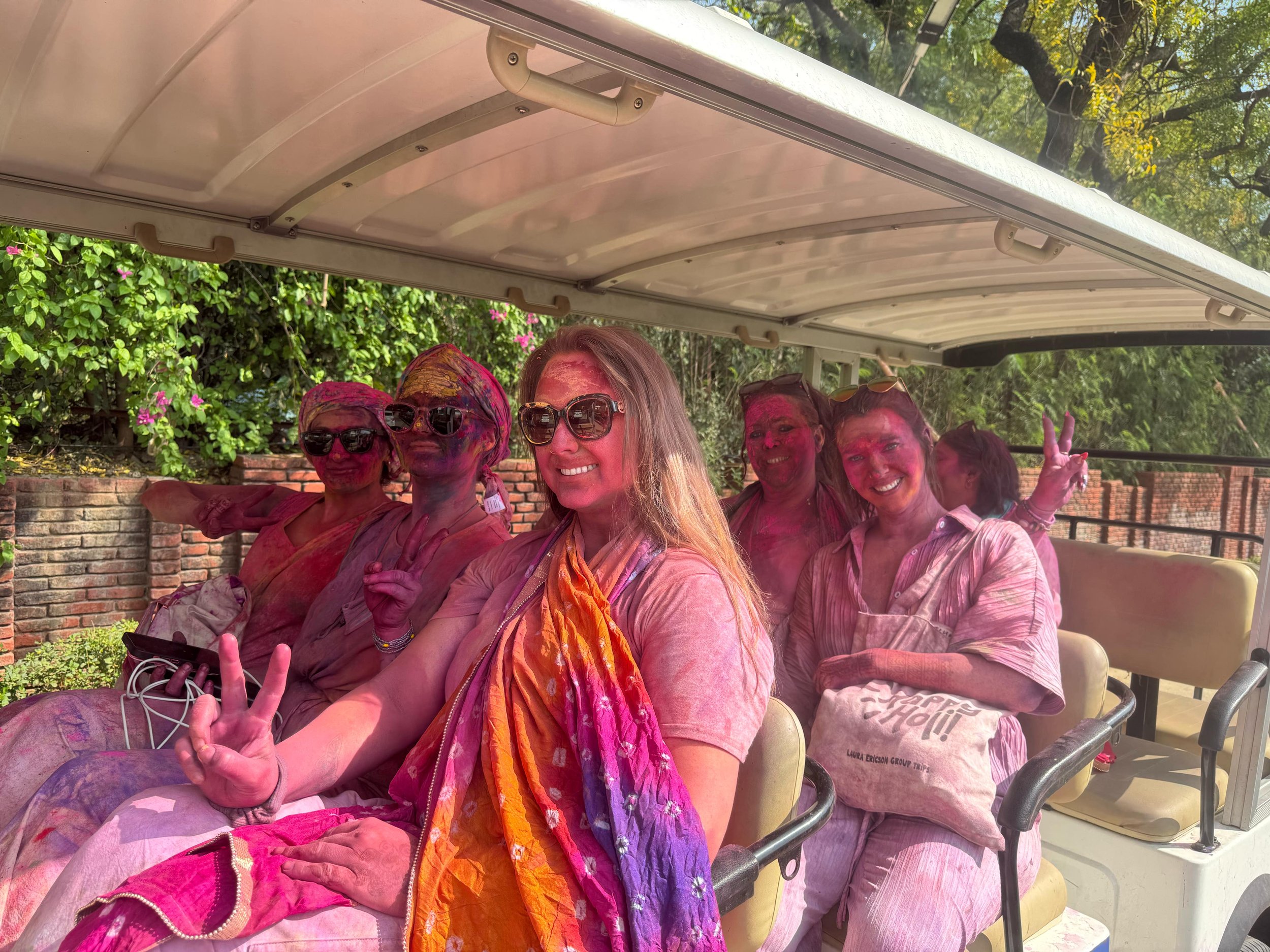 Group covered in colorful powder riding in cart after playing Holi festival in India during cultural immersion trip