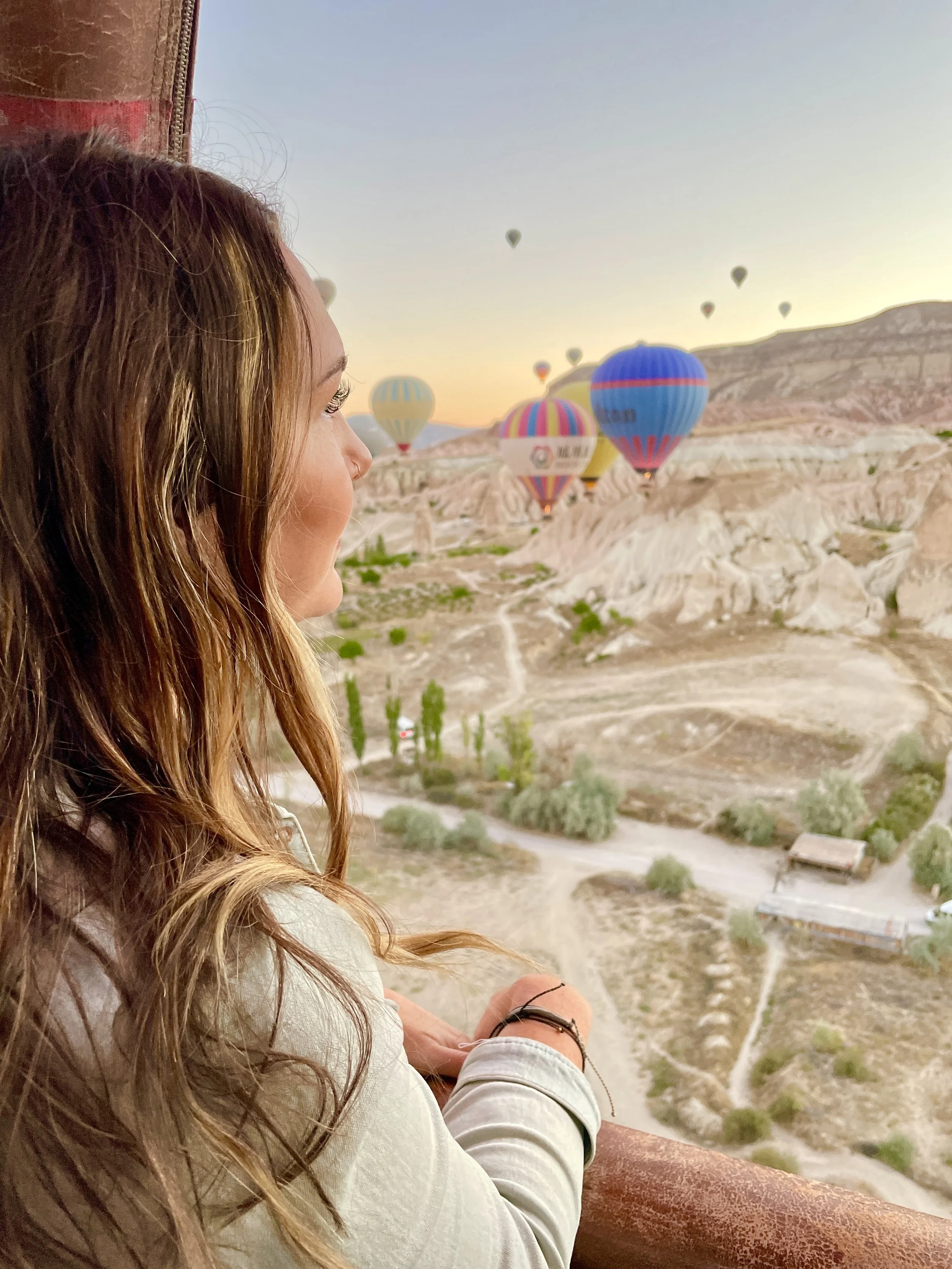 Woman watching hot air balloons at sunrise in Cappadocia, Turkey