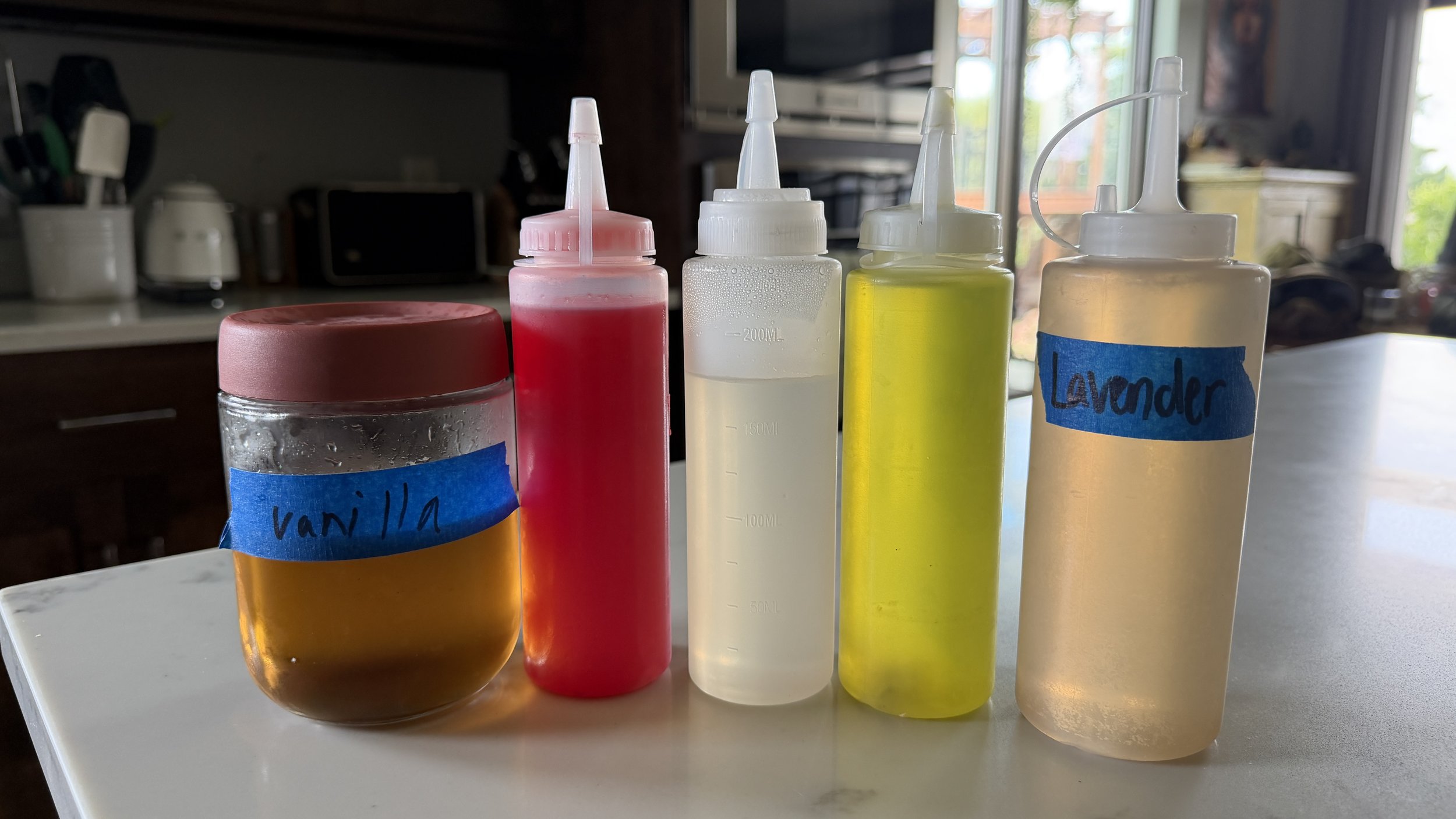 Basil, blueberry basil, thyme, lavender and cucumber simple syrups in jars