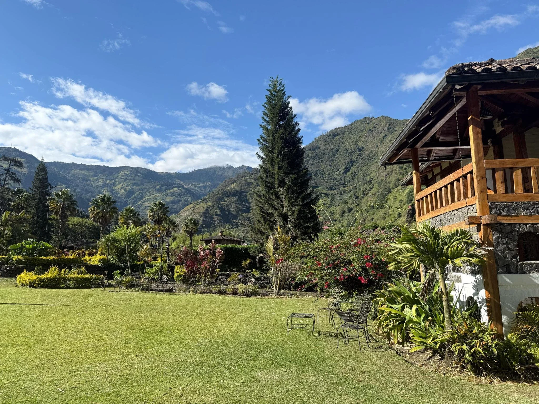 Scenic view of mountain lodge with manicured lawn and gardens surrounded by Andes mountains in Ecuador