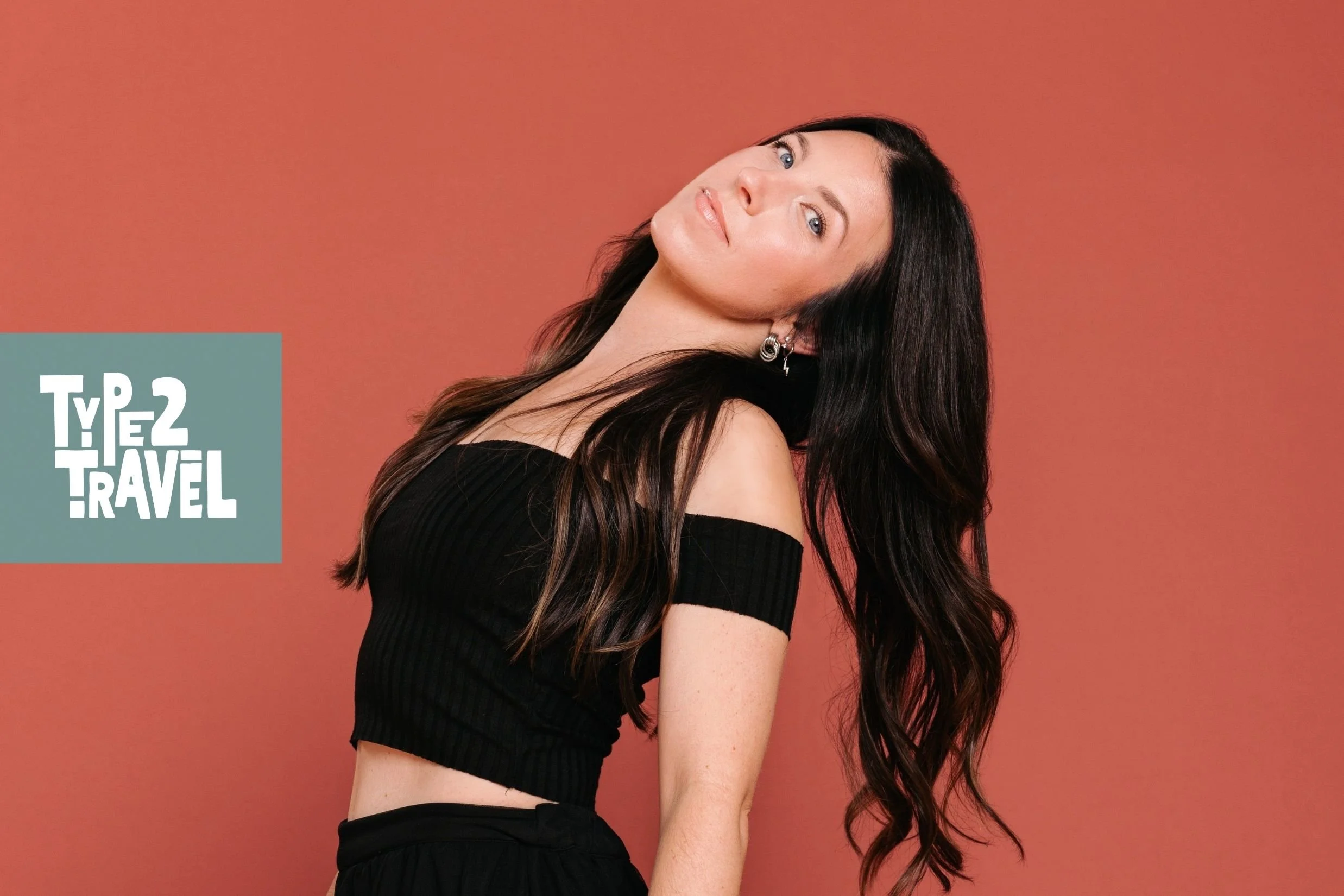 Episode graphic for the Type 2 Travel podcast featuring a dark-haired woman in a black off-shoulder crop top looking over her shoulder against a terracotta-red background, with the Type 2 Travel logo in the upper left corner.