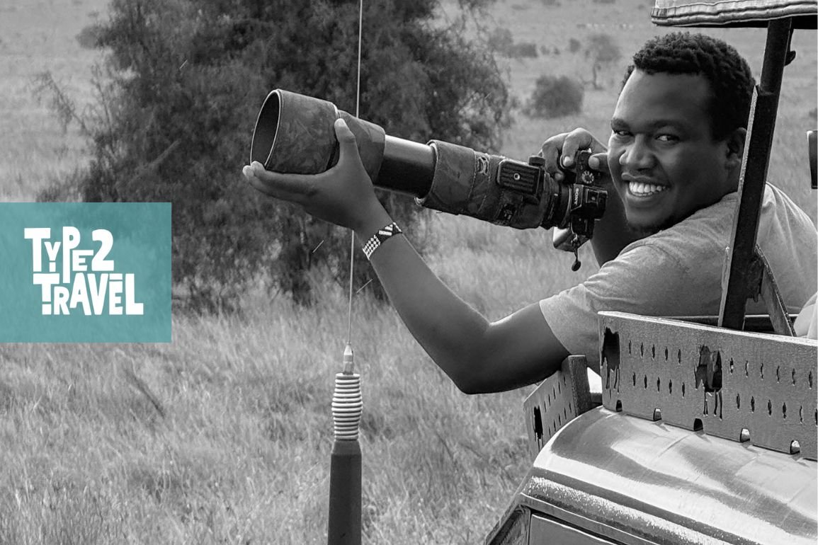 Black and white photograph of Justin Emanuel, a smiling Kenyan wildlife photographer.
