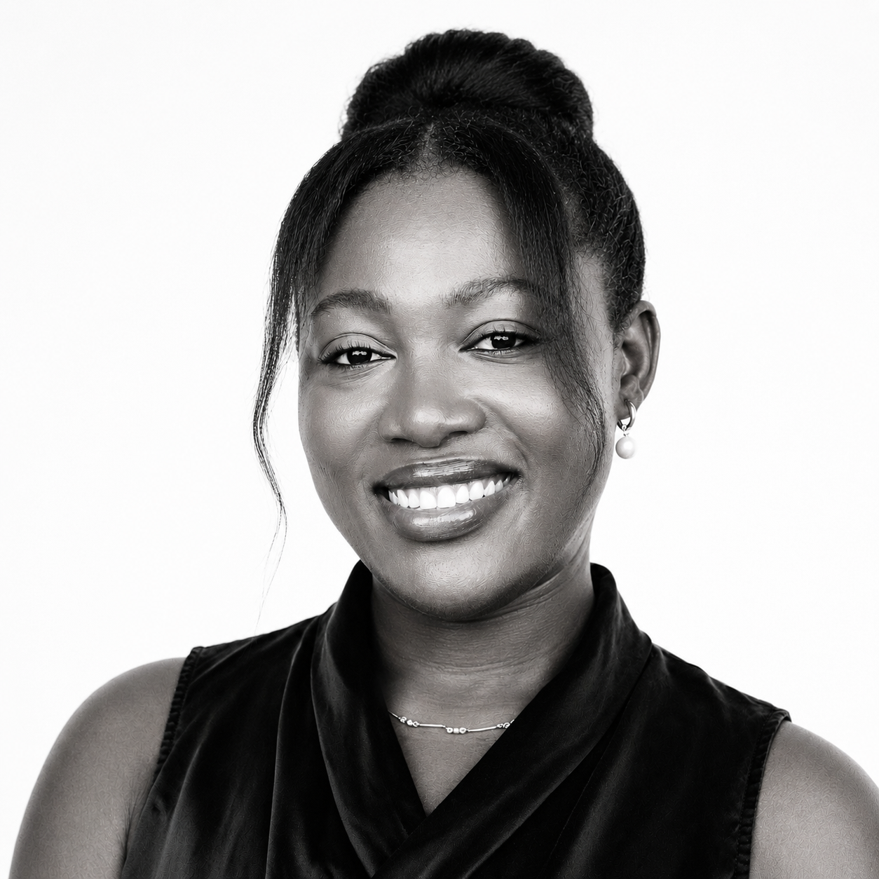 Black and white portrait of a smiling woman with earrings and a pearl necklace.