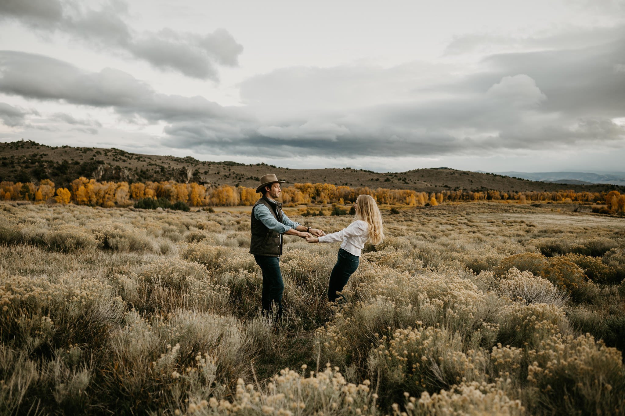 Wyoming wedding, couple dancing in a grassy field with the big cloudy grey skies.