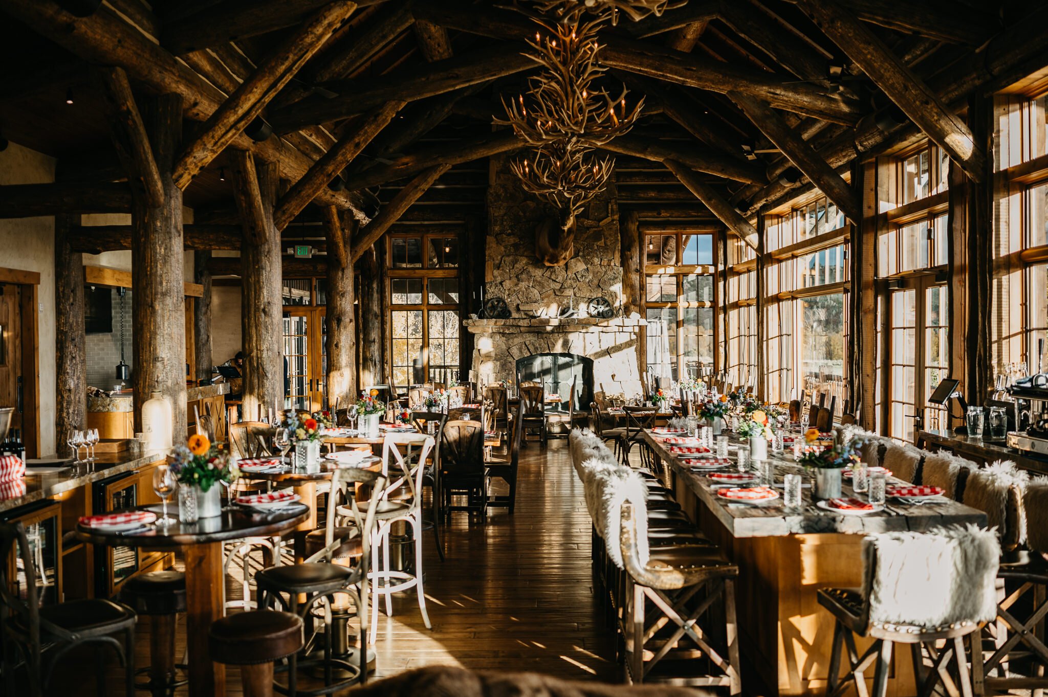 Brush Creek Ranch, Wyoming dinning room set for wedding reception. Rustic room with set for dinner checkered red and white napkins and yellow, orange and blue flowers in the center of each table.