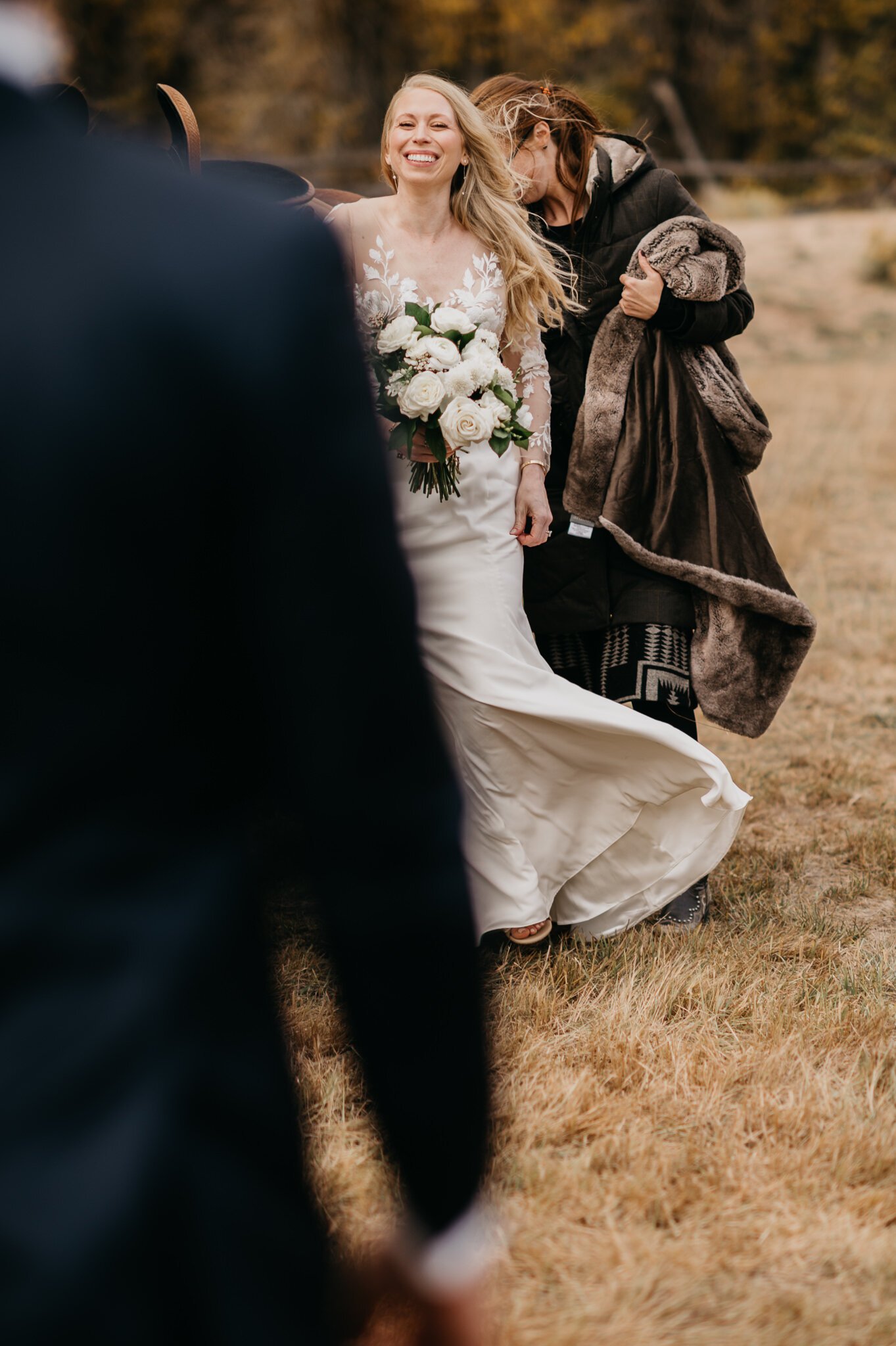 Bride in white wedding dress walking up to meet groom, with the horse she rode to ceremony in the background. 