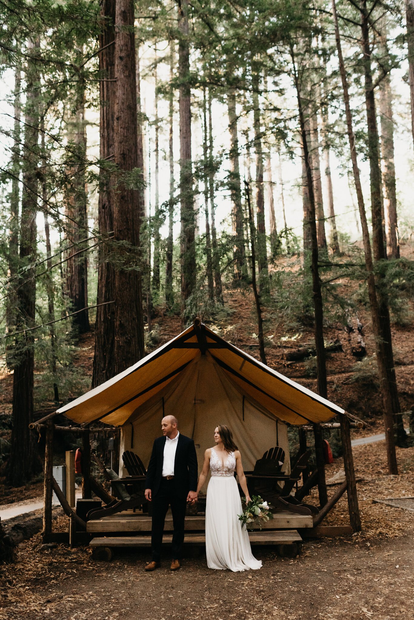 newly married couple in wedding attire in front of clamping tent in Ventana Big Sur