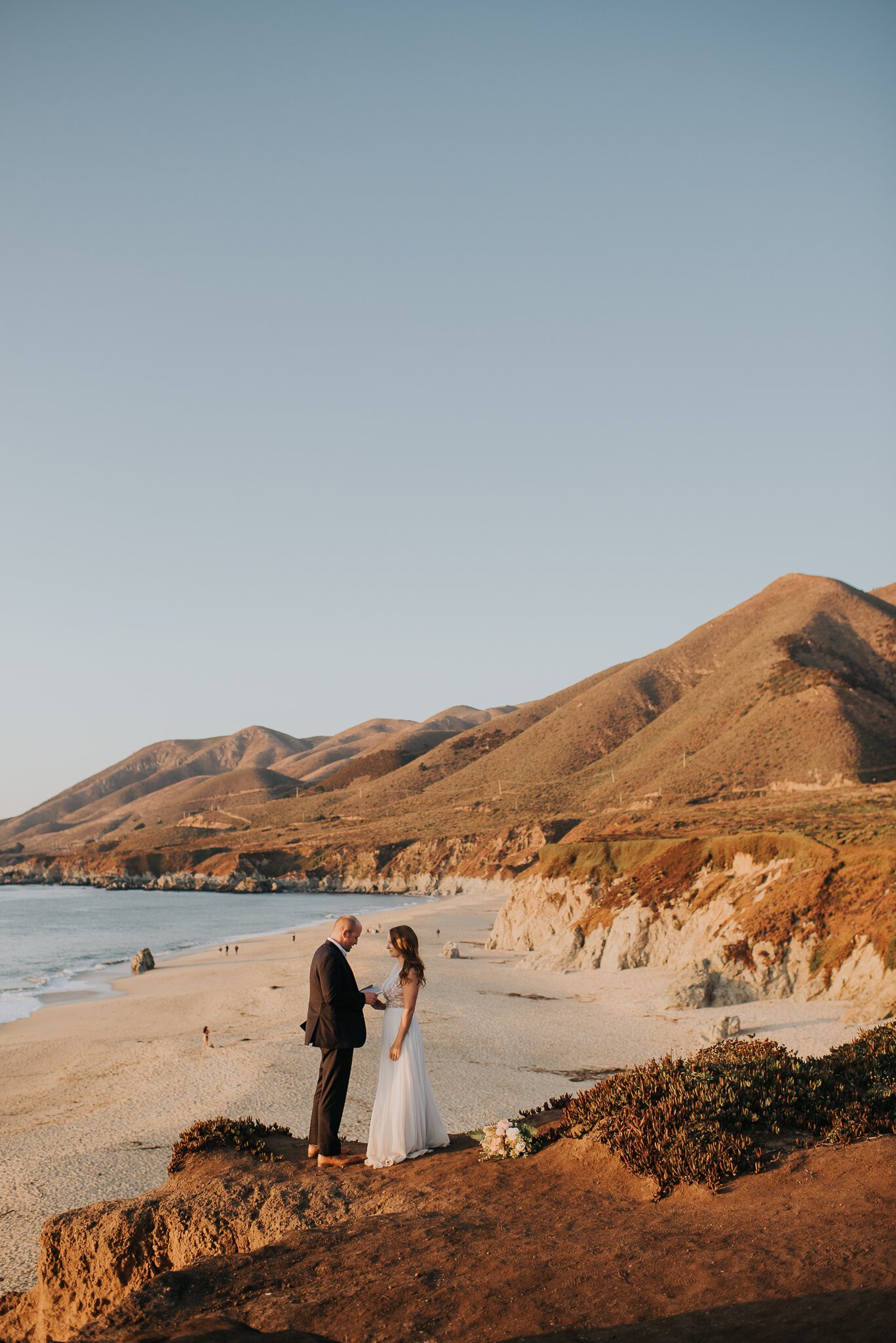 Ventana Elopement Cliffside bride and groom exchanging vows, beach in background