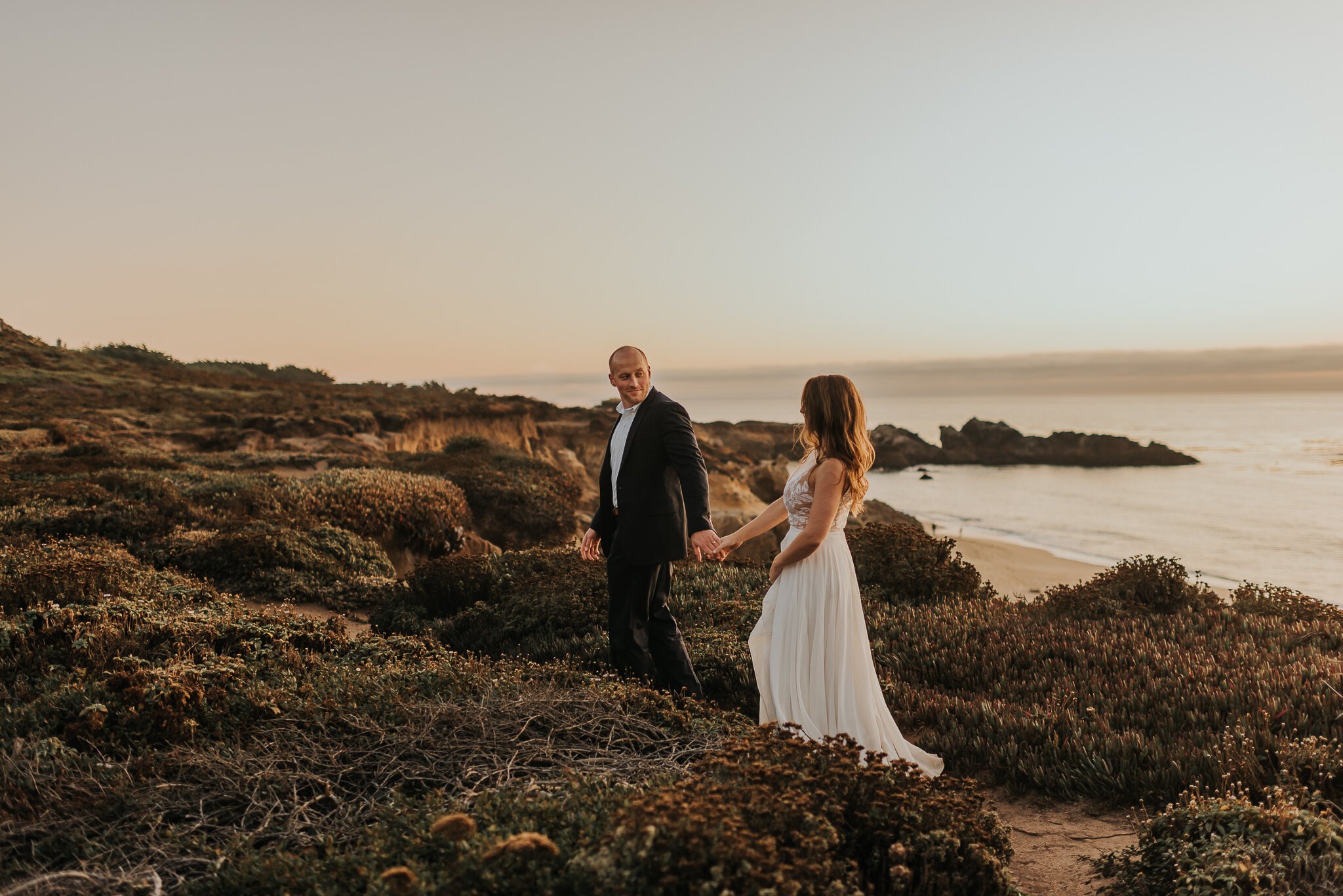 Big Sur Elopement bride and groom walking on path above Pacific Ocean Big Sur