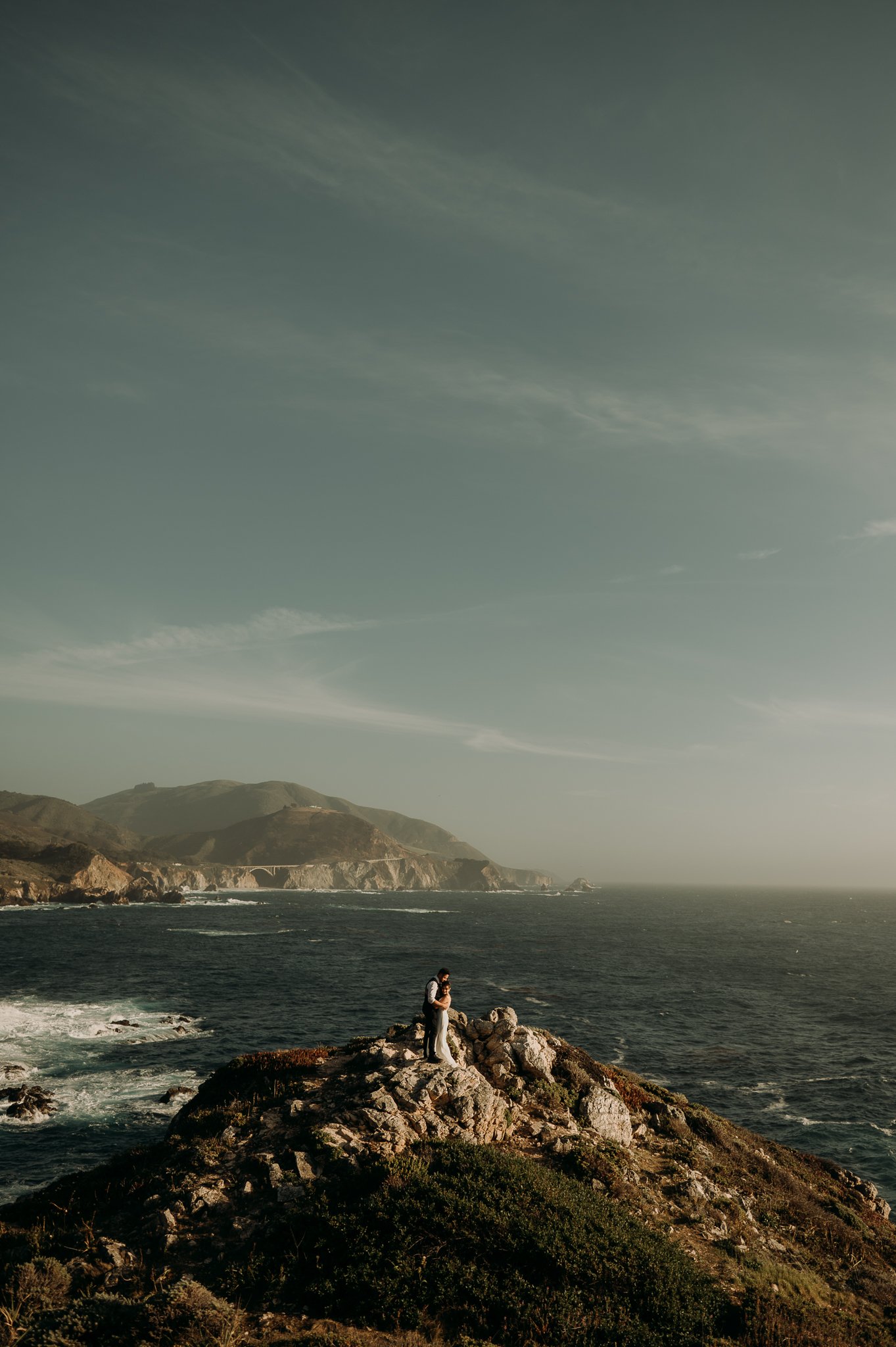 Couple posing on cliffs overlooking the Pacific Ocean Big Sur California