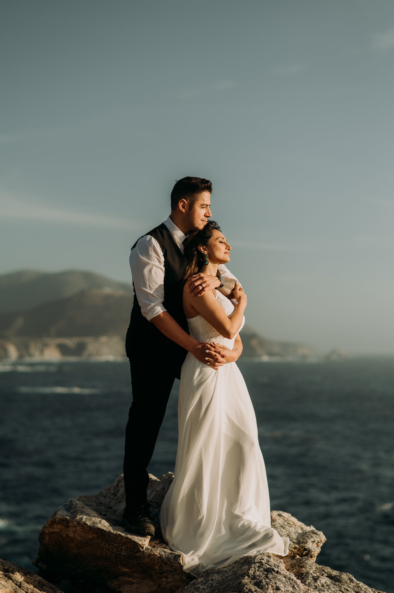 Couple posing on cliffs overlooking the Pacific Ocean Big Sur Californiaa