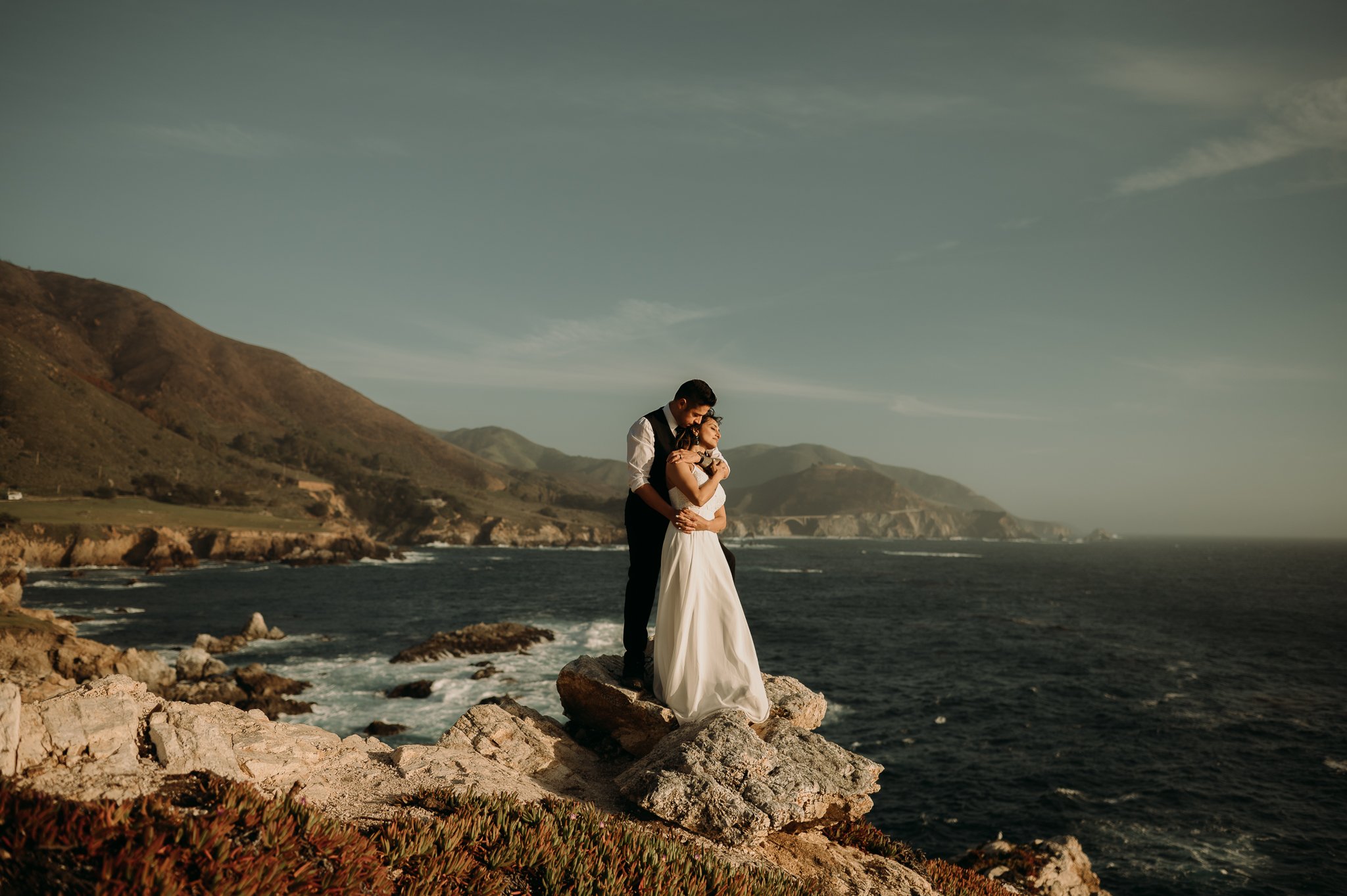 Couple posing on cliffs overlooking the Pacific Ocean Big Sur California