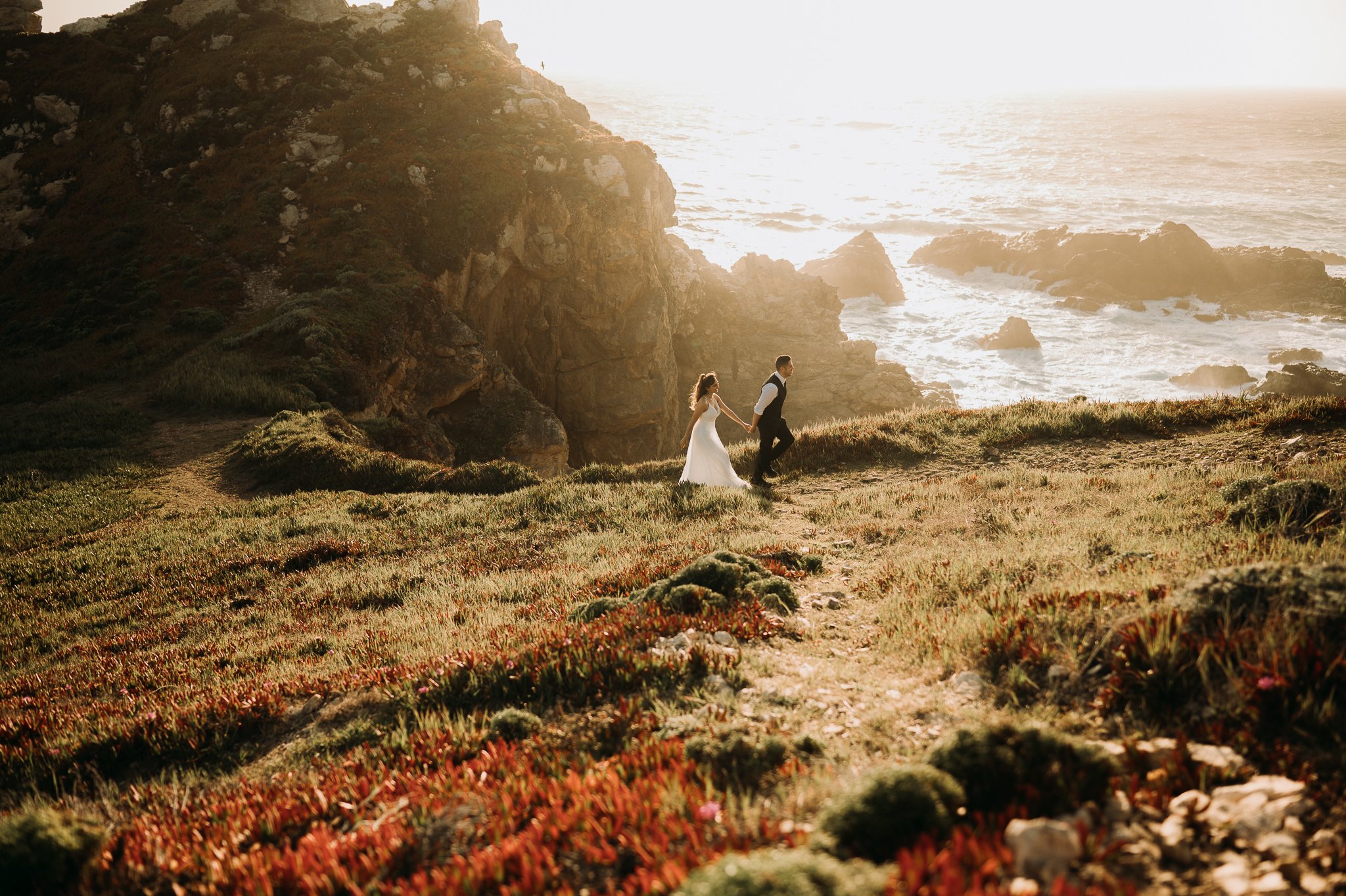 Couple walking on trail above Pacific Ocean Big Sur