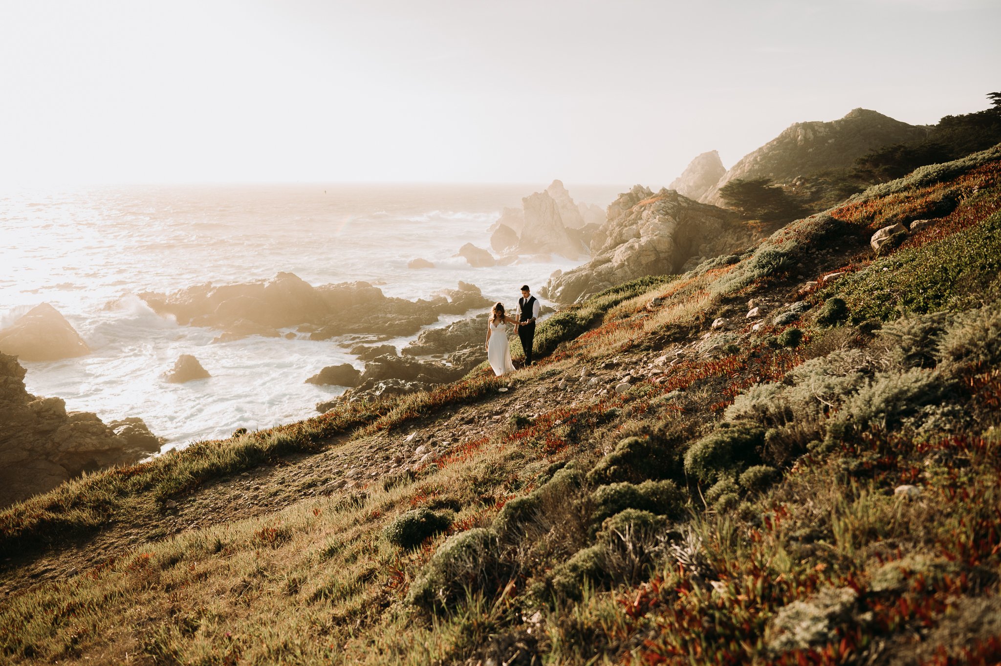 Couple walking on trail above Pacific Ocean Big Sur