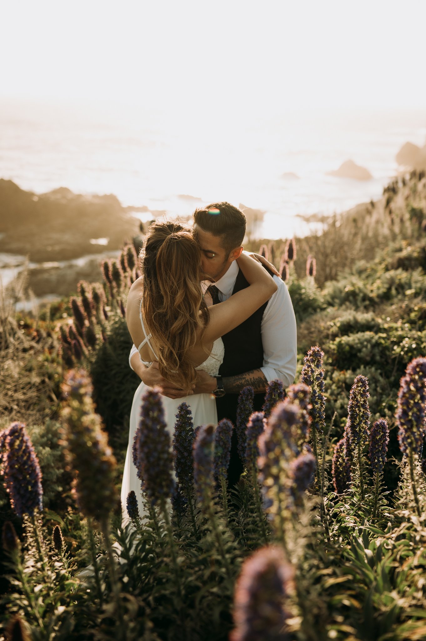 Newlyweds photo session couple hugging in flowers cliffside Big Sur California