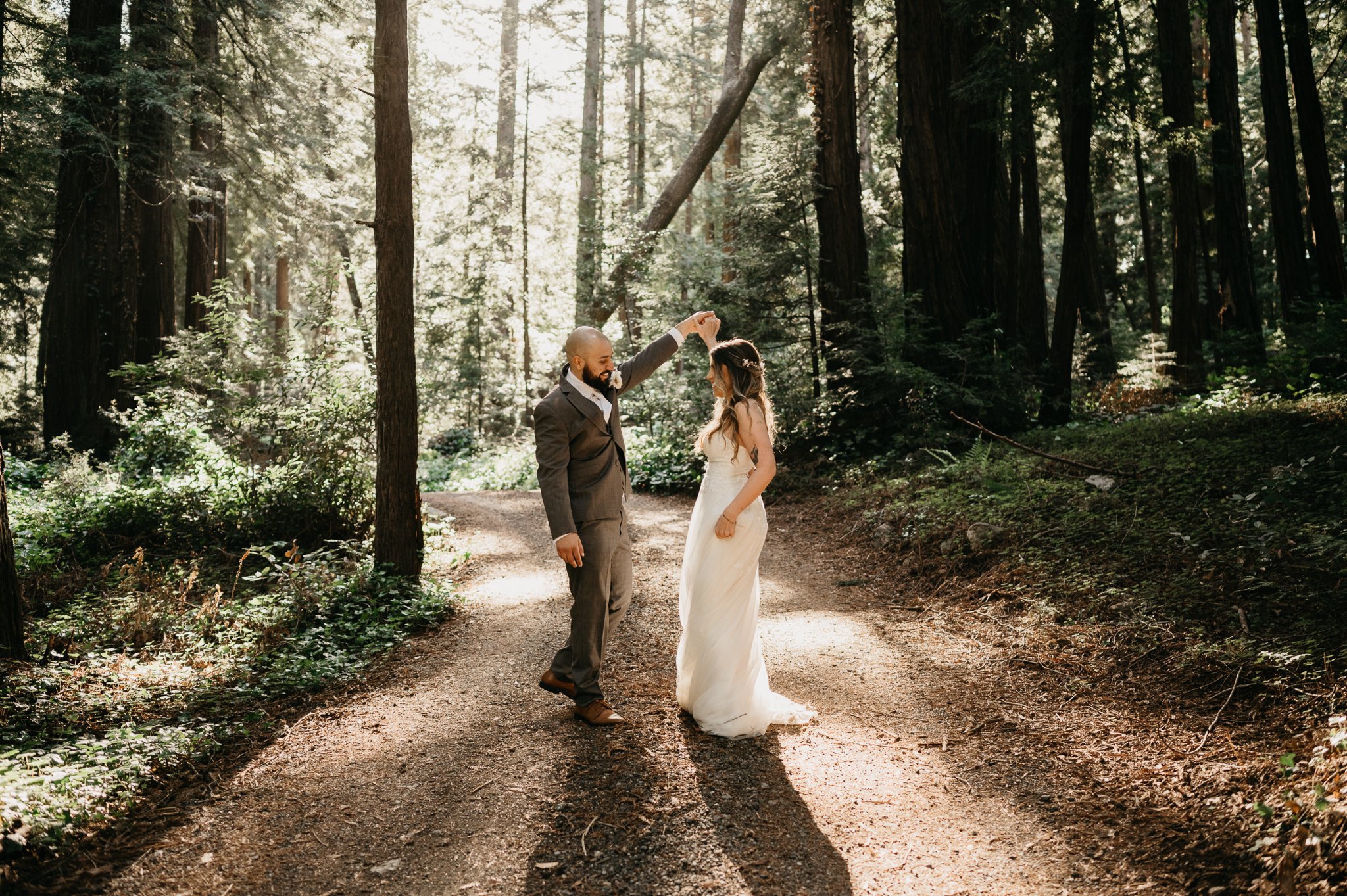  bride and groom dancing on path under redwoods before elopement ceremony in Big Sur California