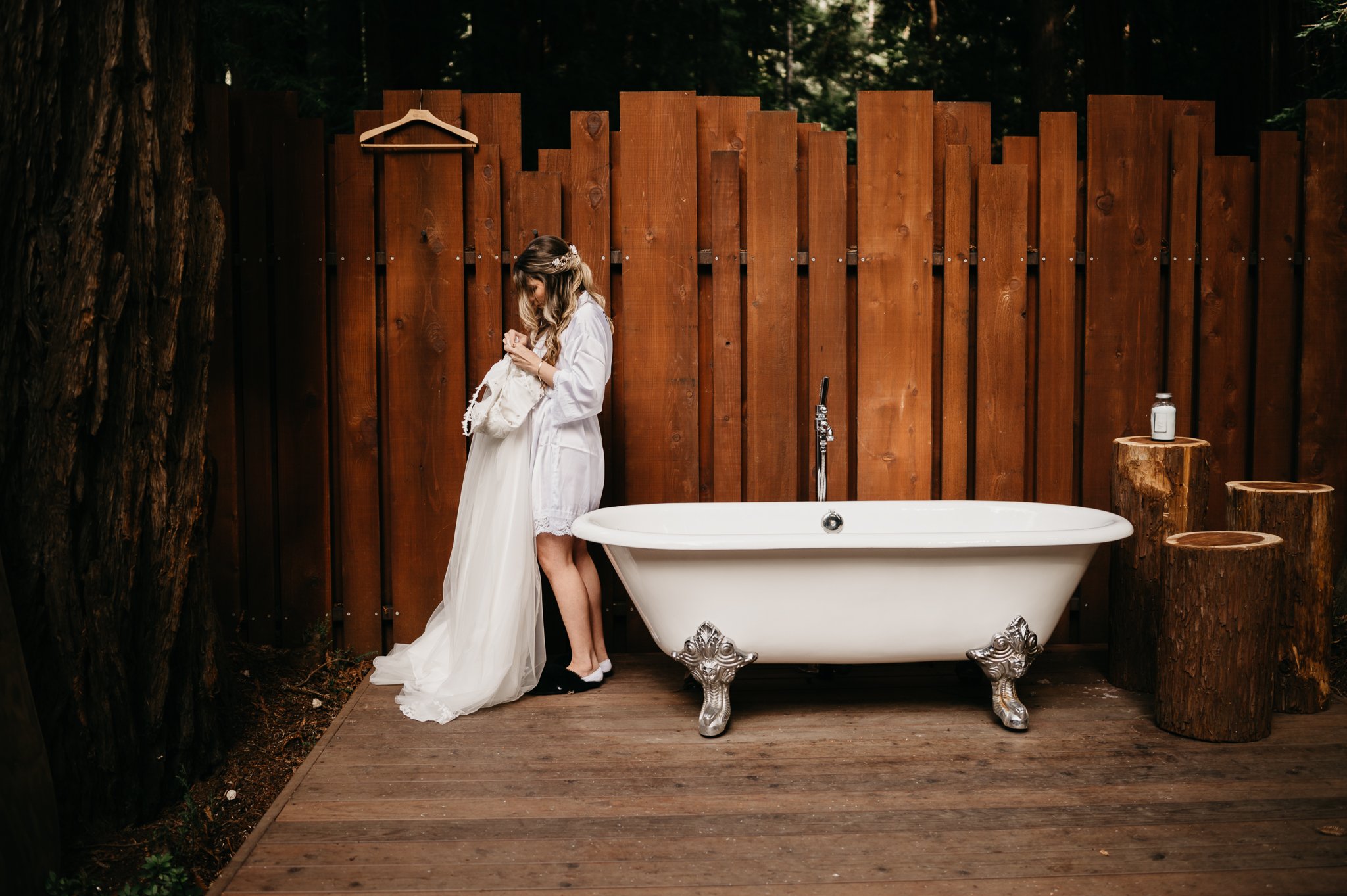 Glen Oaks elopement bride beside and old claw-foot tub adjusting dress dressed in robe and slippers