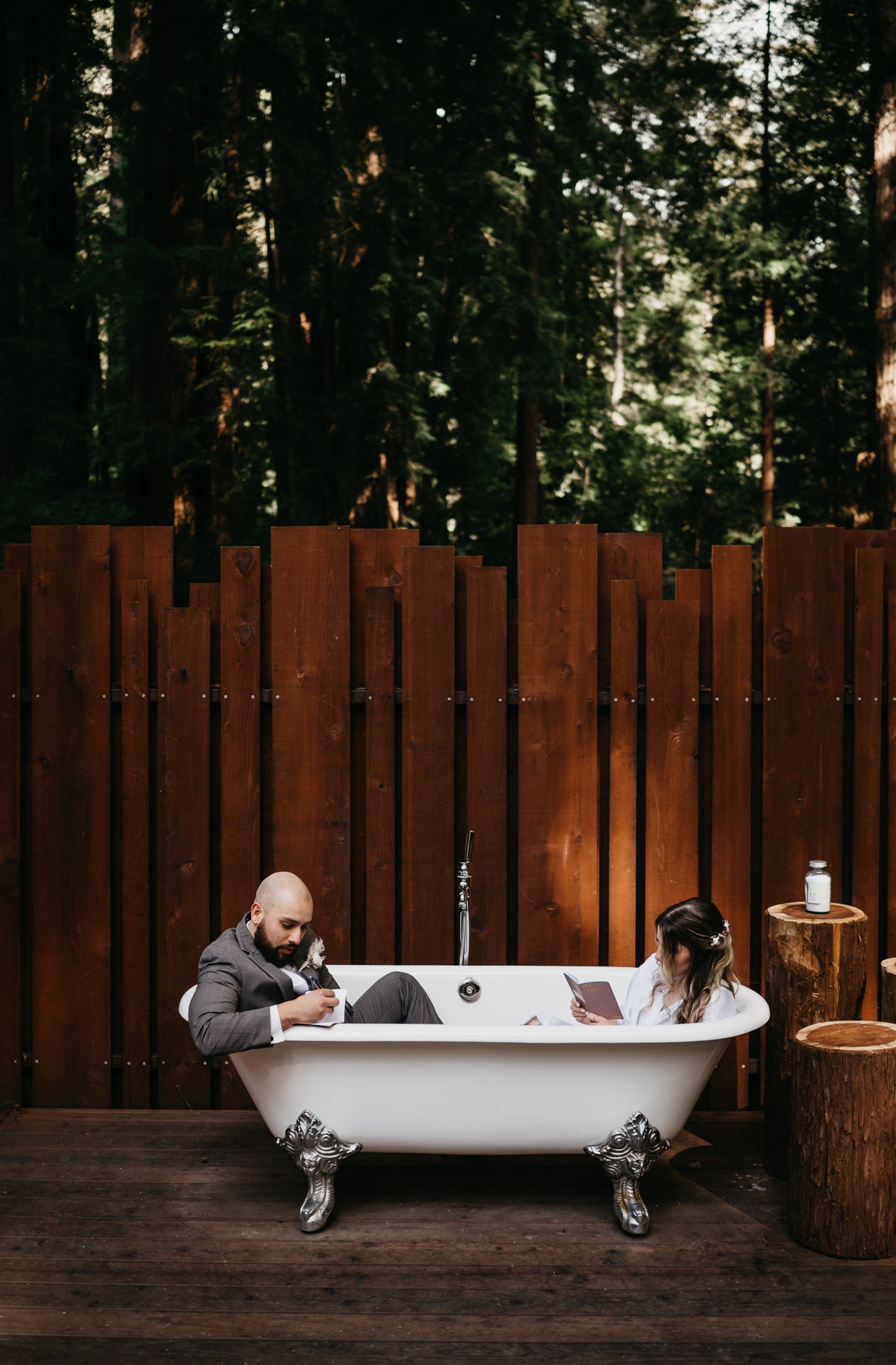 Bride and groom in claw-foot tub checking vow books before elopement ceremony Big Sur