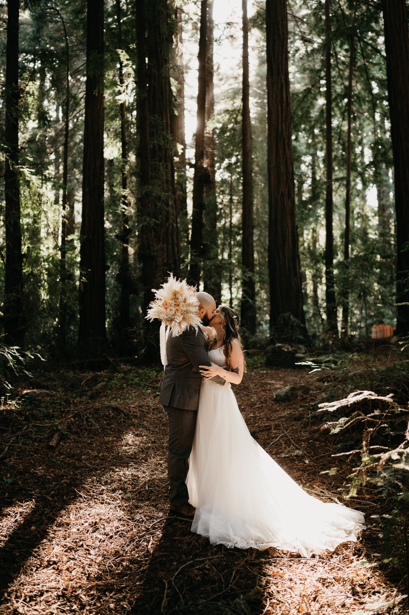  bride and groom kissing under tall redwood tress after elopement ceremony in Big Sur California