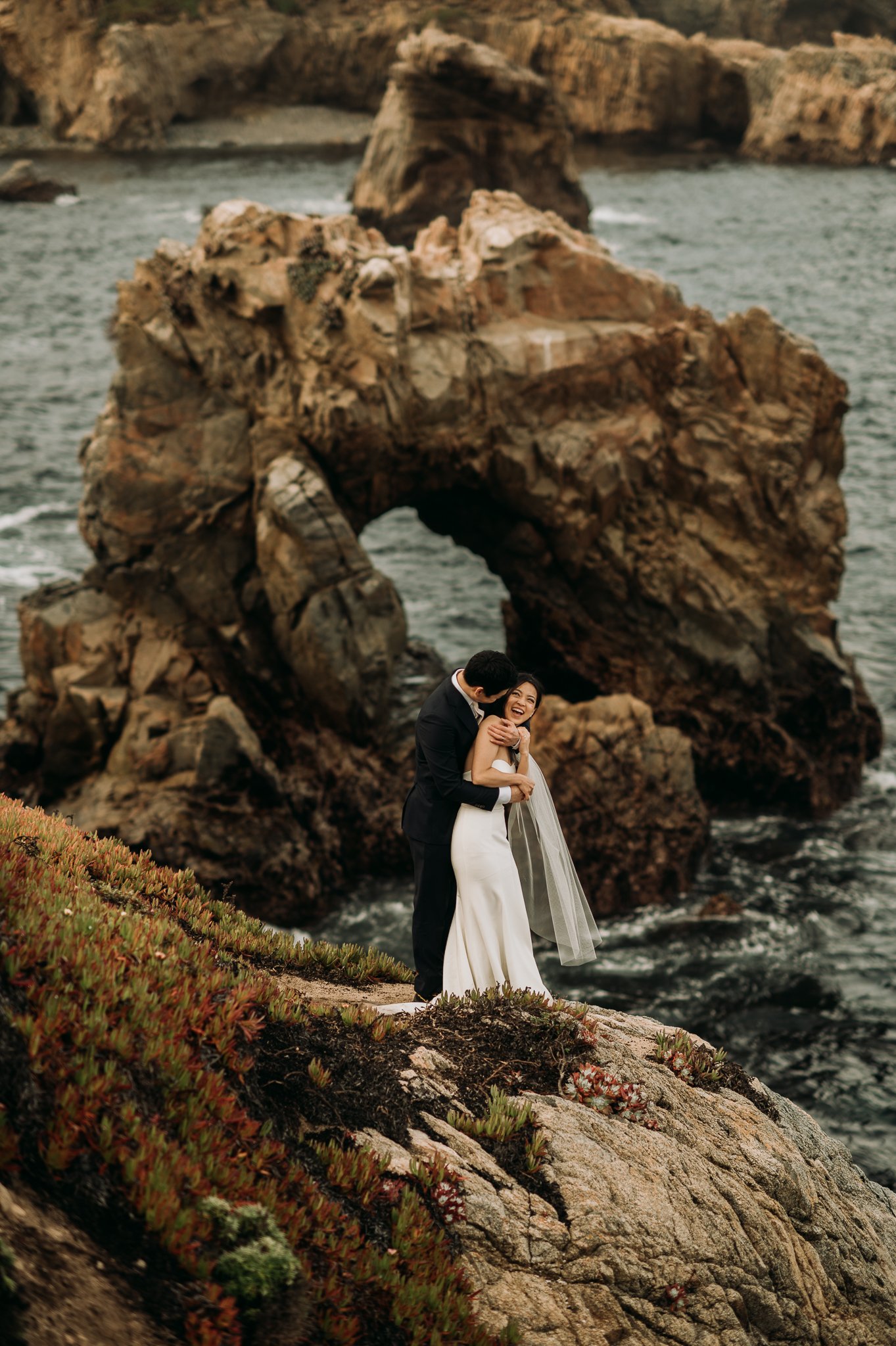 Elopement couple posing cliffside Big Sur with key hole rock in background