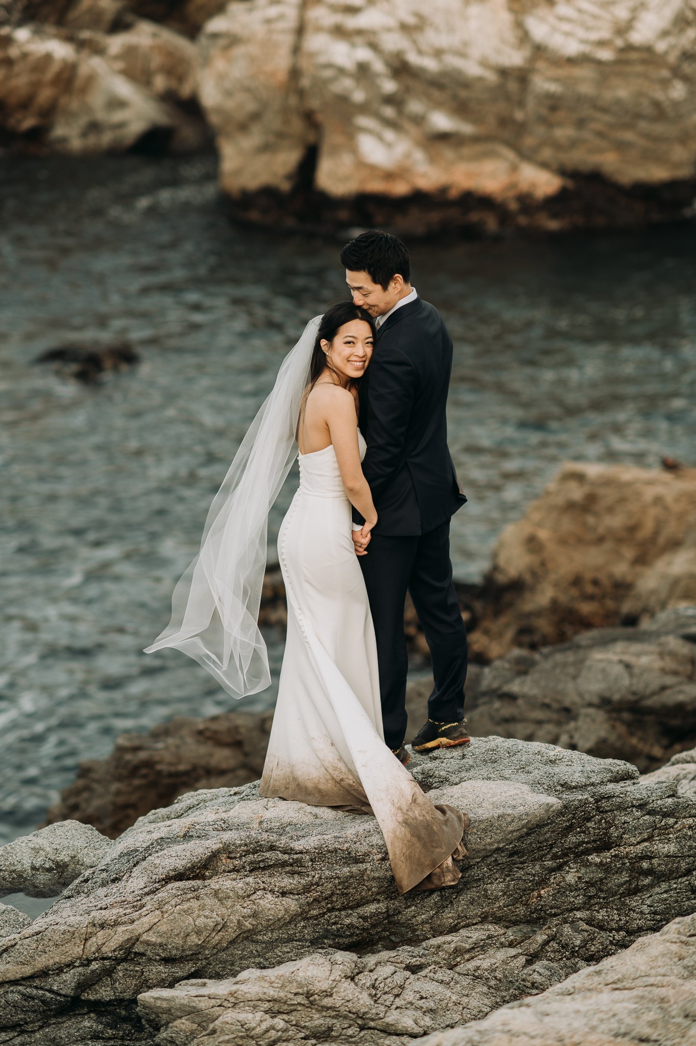 Bride and groom embracing  on cliff with Pacific Ocean in background Big Sur Elopement