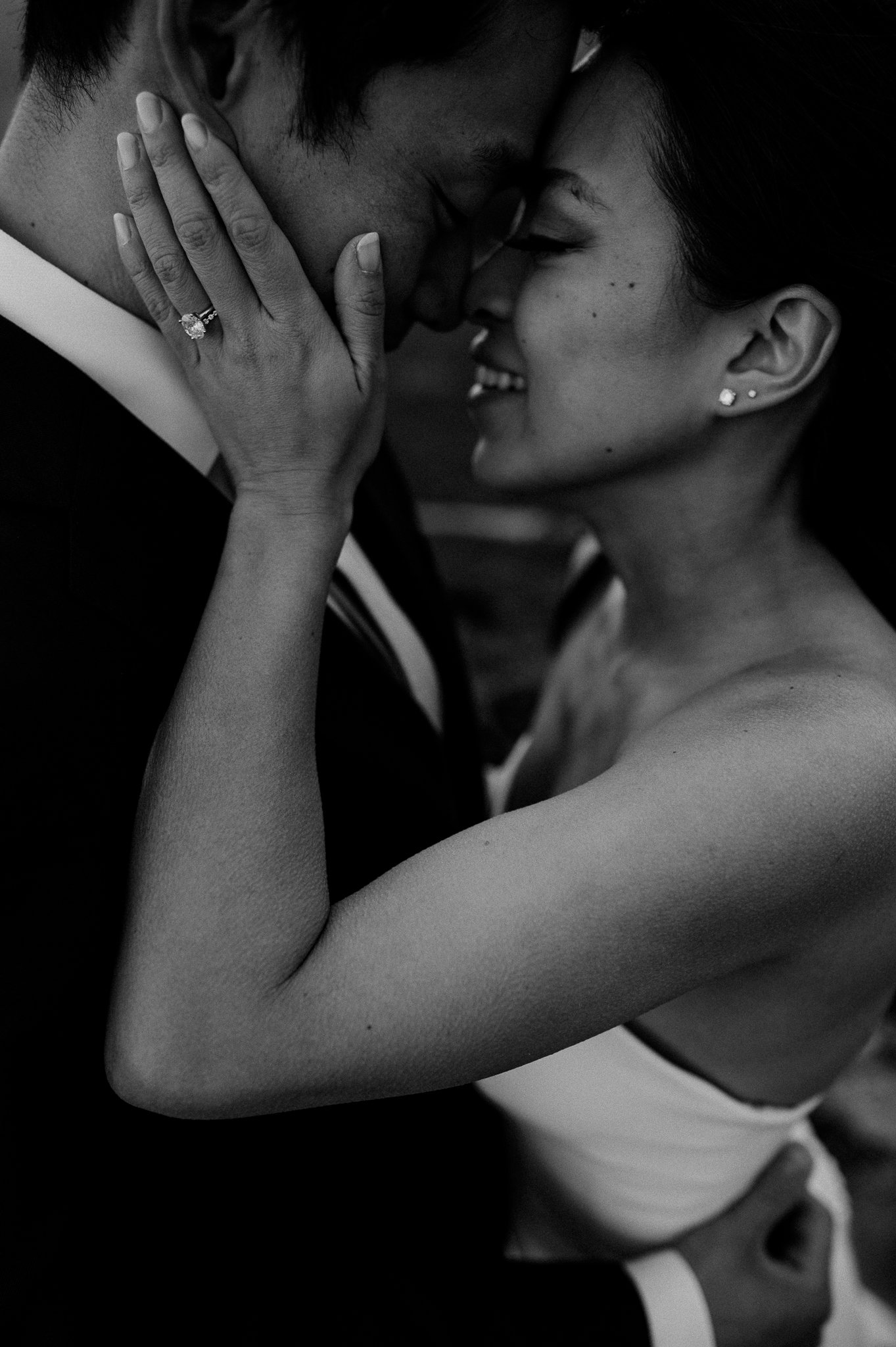 close up black and white photo of bride and groom face to face brides hands on grooms face