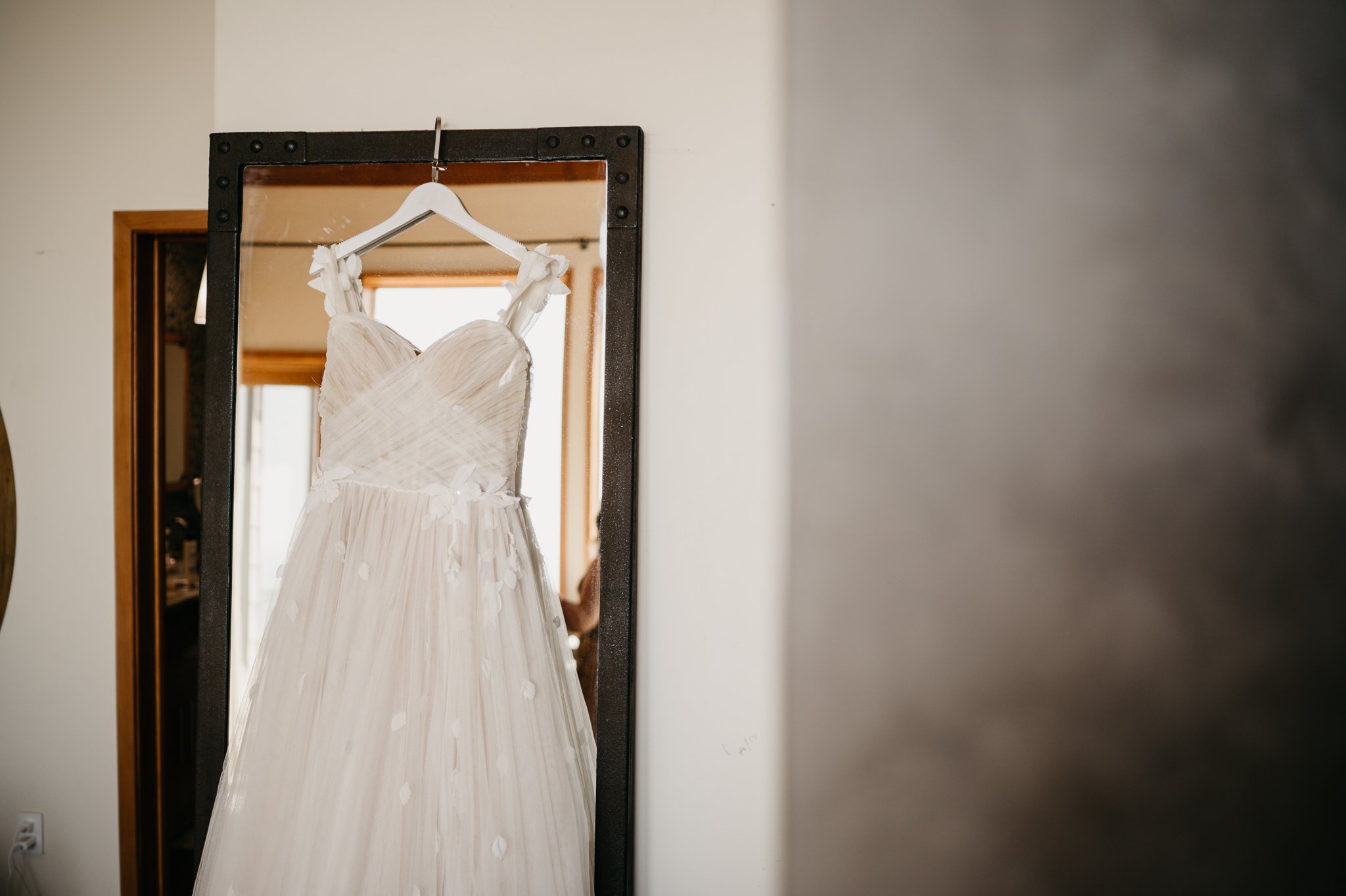 Brides wedding dress hanging in door frame at Wind and Sea Big Sur