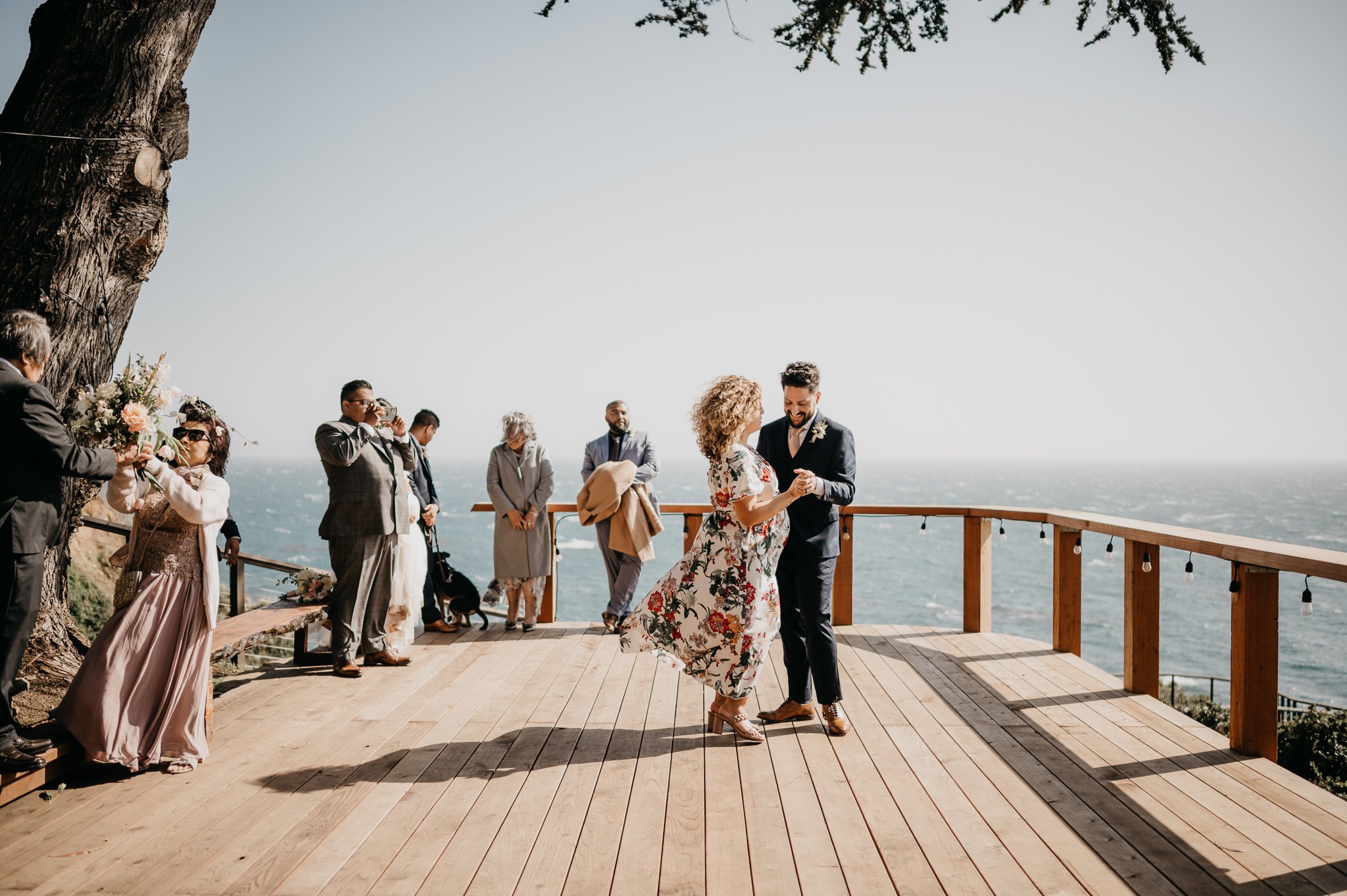 Groom dancing with wedding guest on deck in garden at Wind and Sea Big Sur