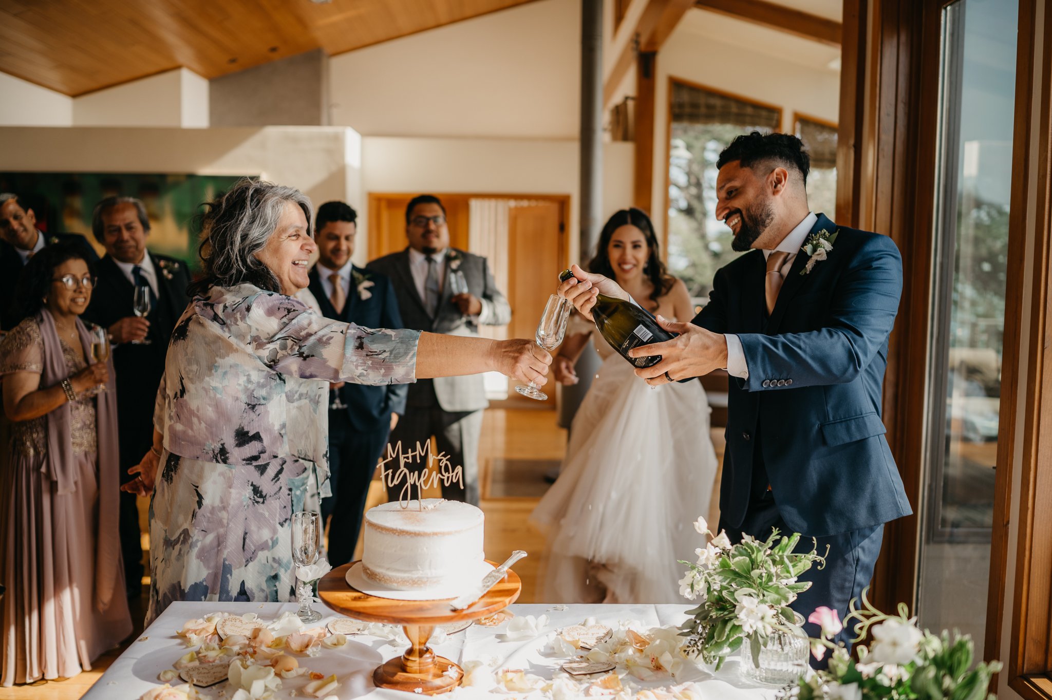 groom pouring champange for his mother with bride in background