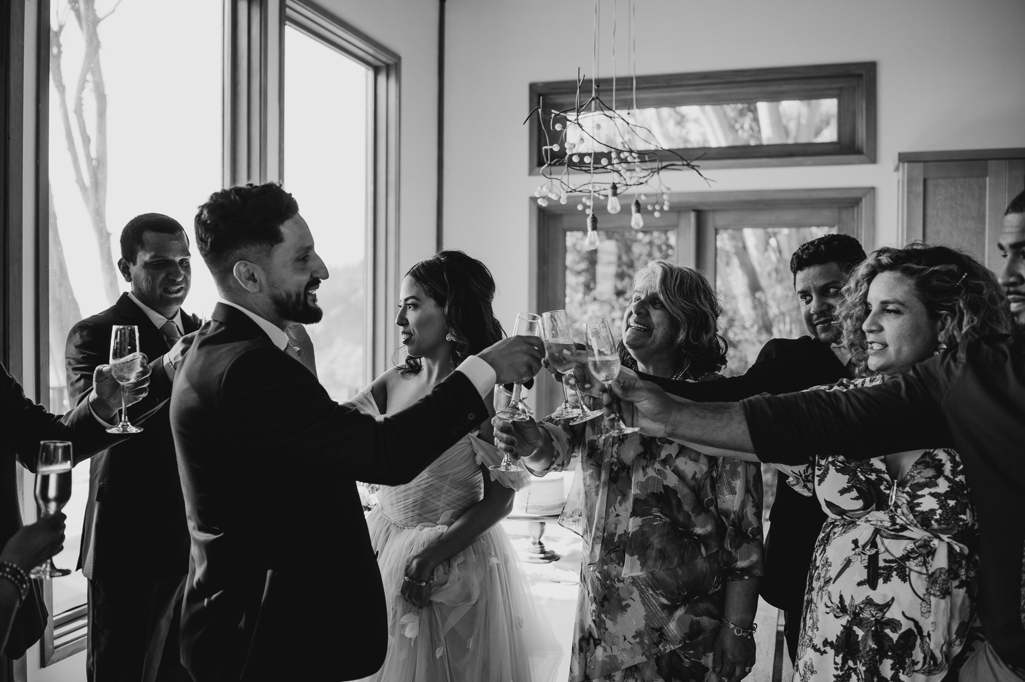 black and white of bride and groom toasting with guests