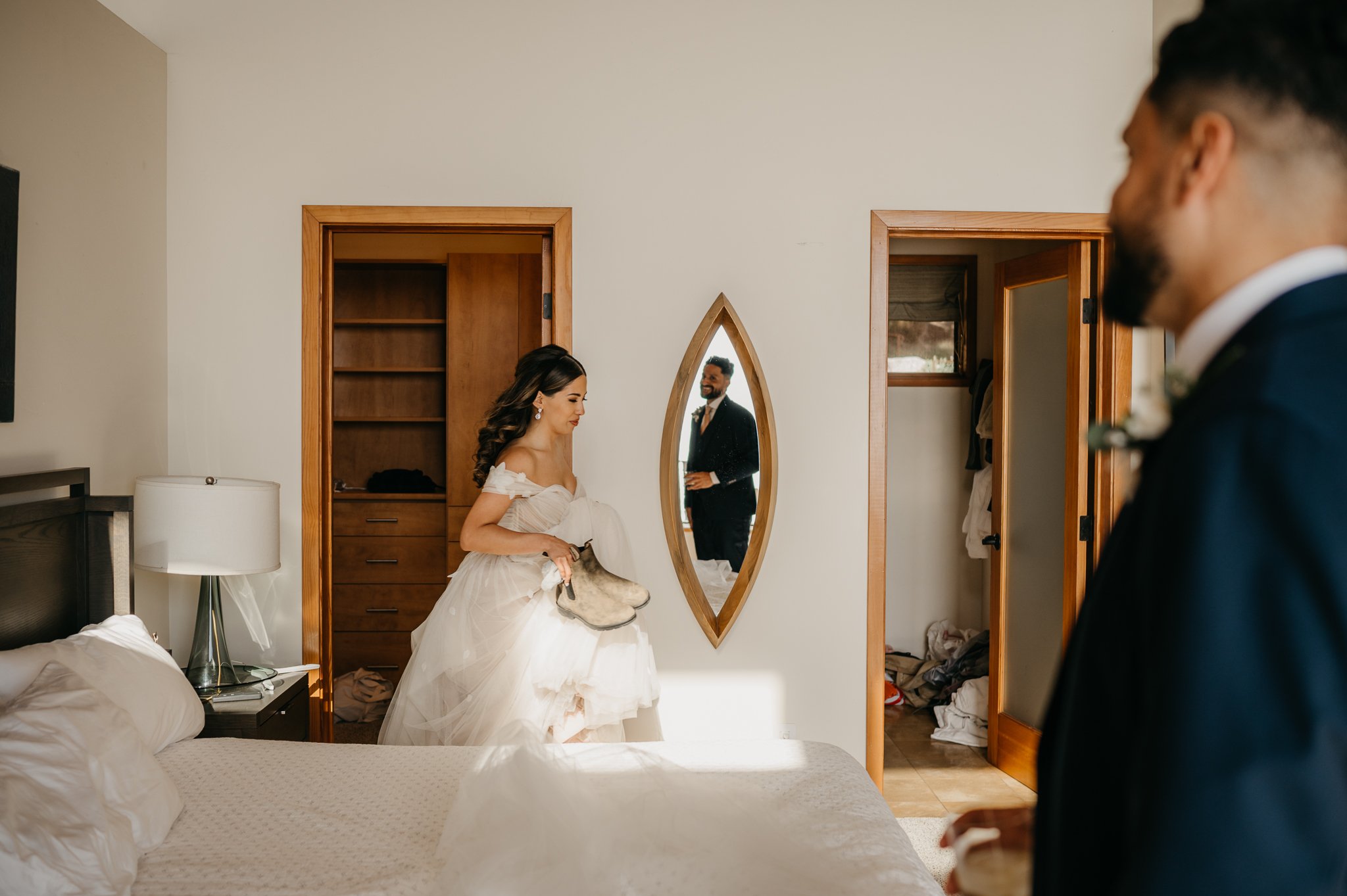 Bride and groom in private room changing shoes with groom's reflection in mirror smiling at bride 
