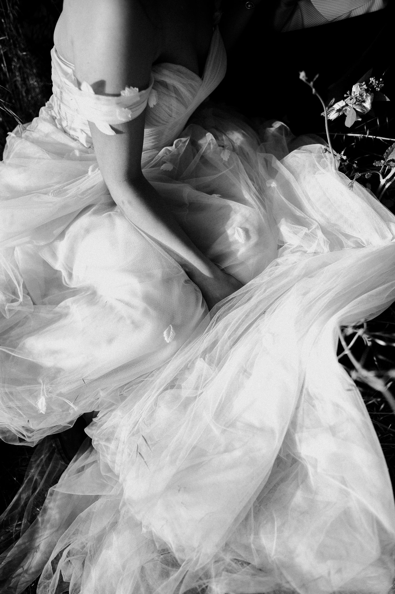 Black and white photo of bride in wedding dress sitting in Big Sur meadow